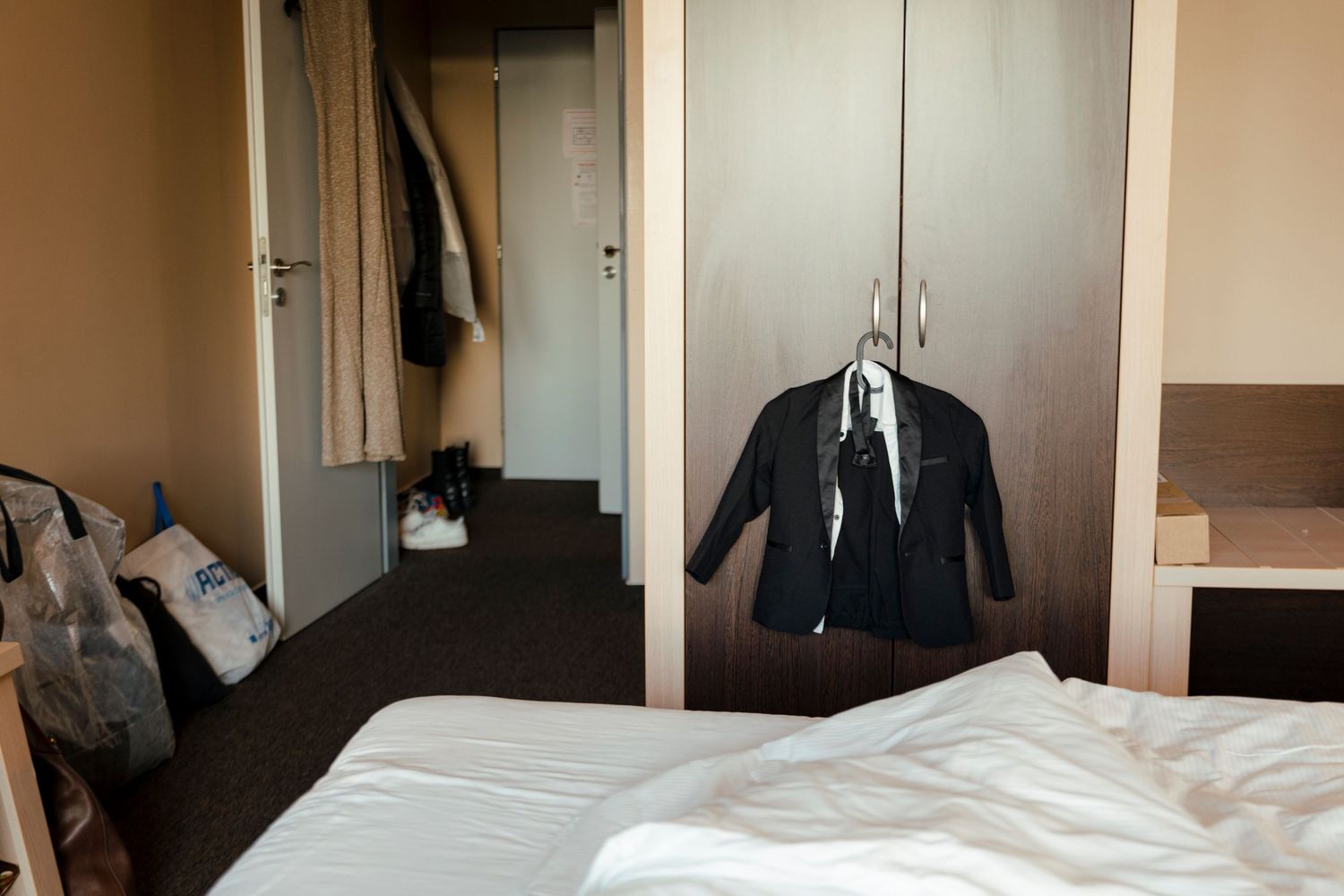 Interior view of empty hotel rooms with white beds and neutral decor.