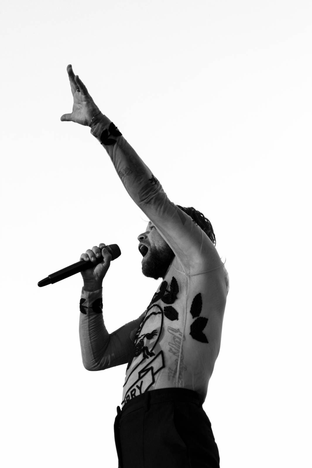 Dramatic black and white silhouettes of performers on stage with microphones and energetic poses.