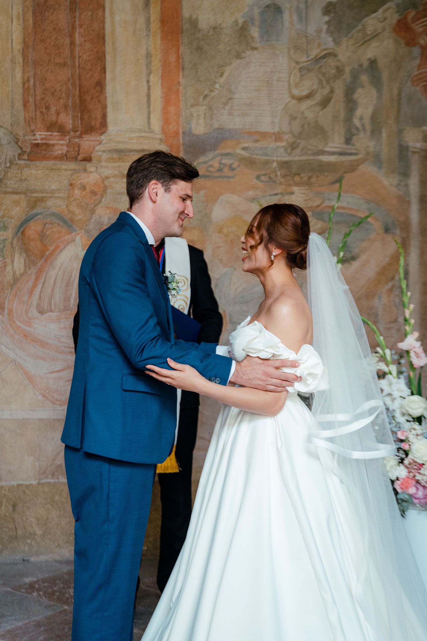 Romantic first dance moment captured against ornate stone wall backdrop.