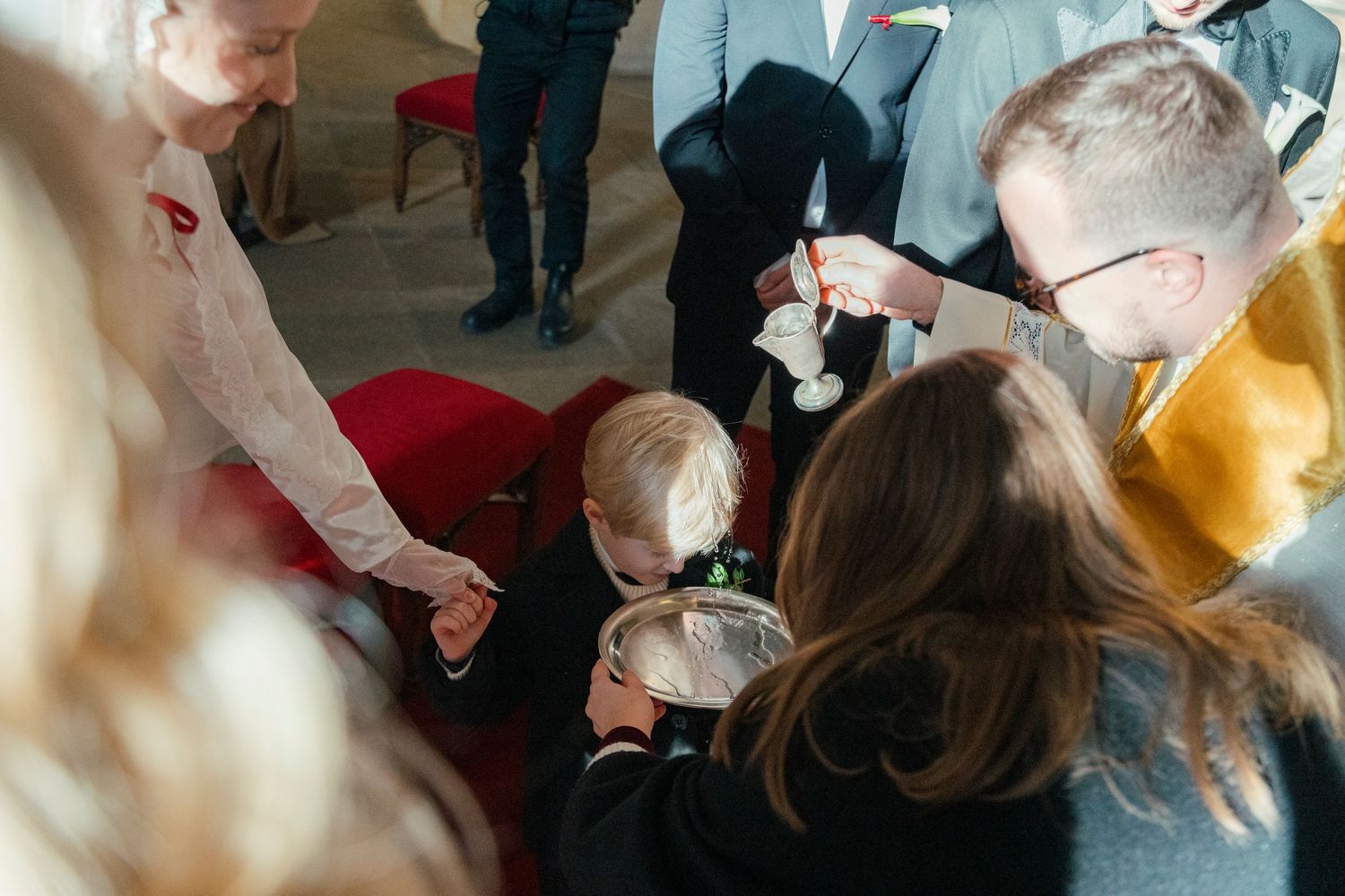 A group of people huddle together examining something in their hands during an indoor gathering.