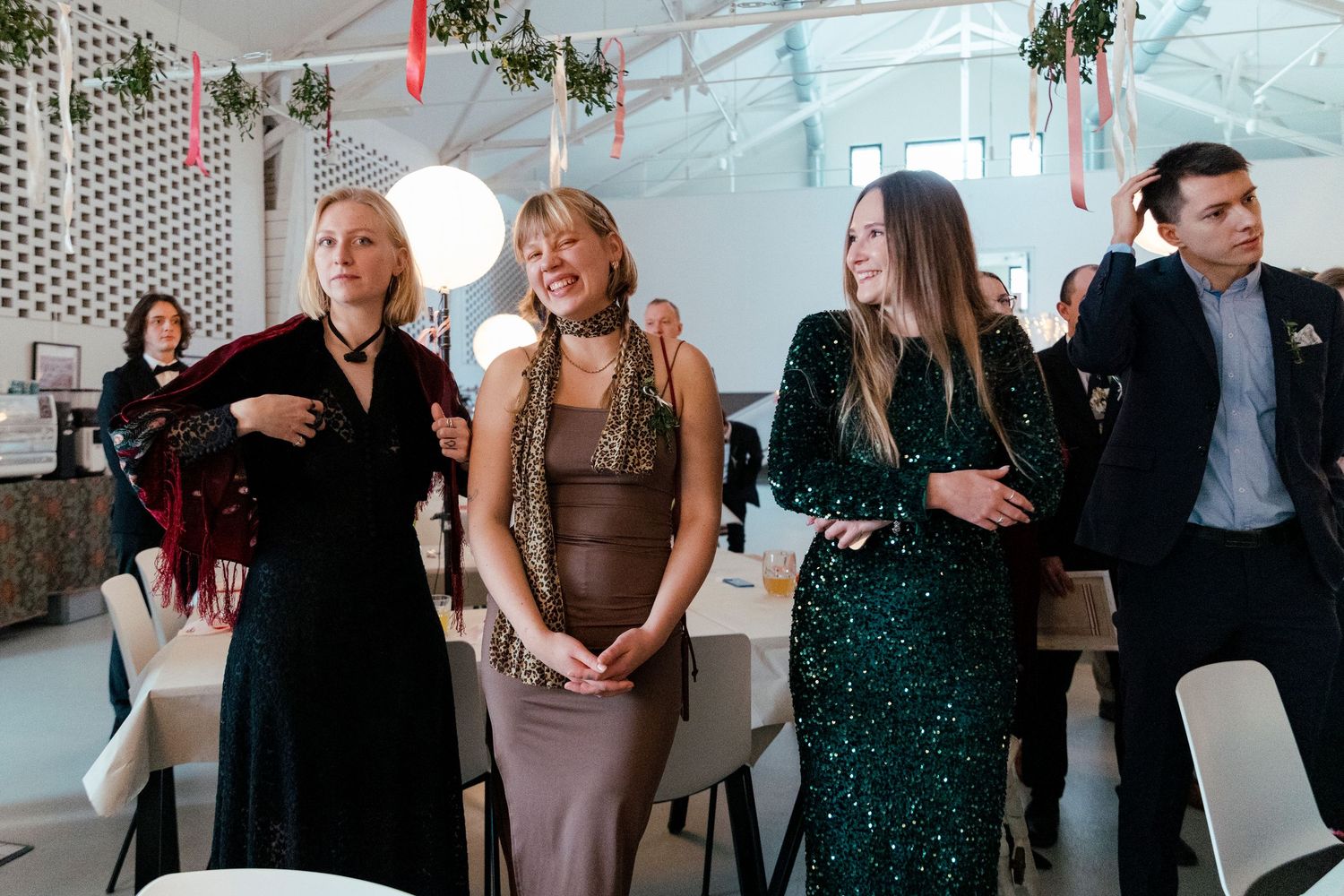Wedding party members mingle and chat during an elegant indoor reception with modern decor.