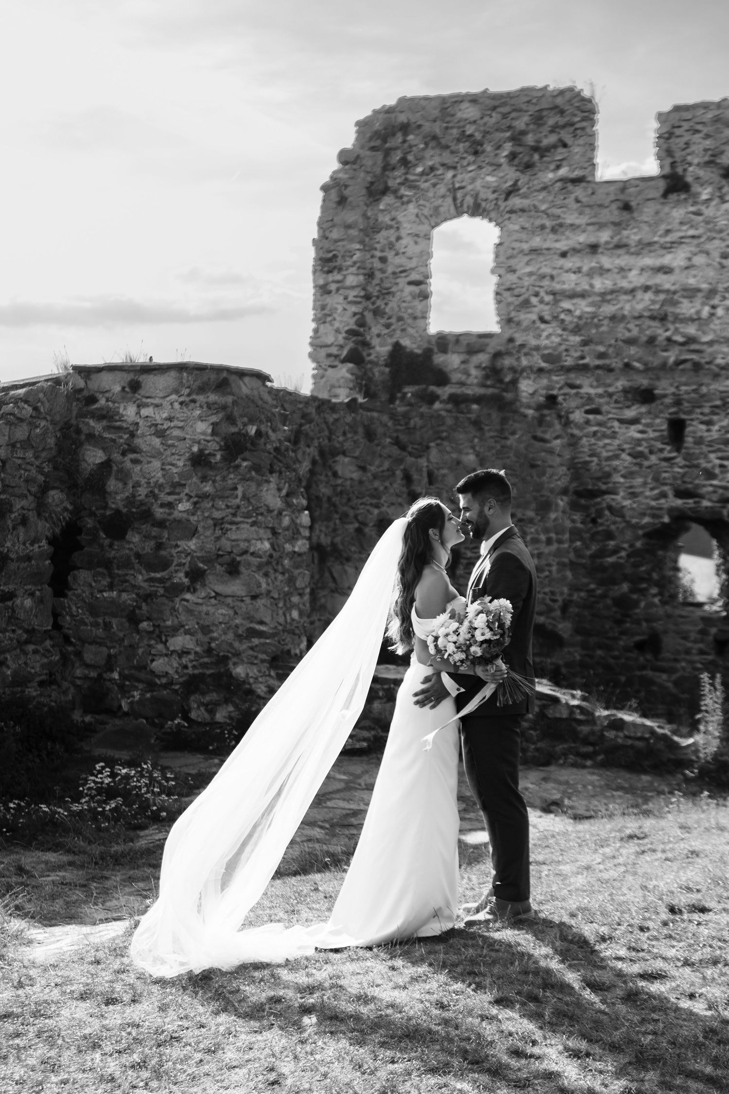 Black and white wedding photos captured against dramatic castle ruins backdrop.
