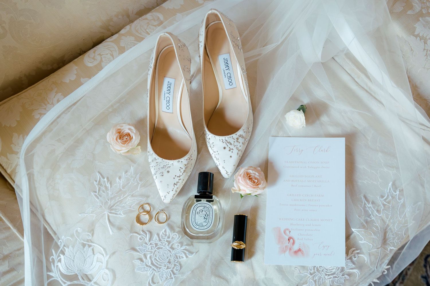 Wedding details flatlay with white shoes, invitation, and delicate lace on light background.