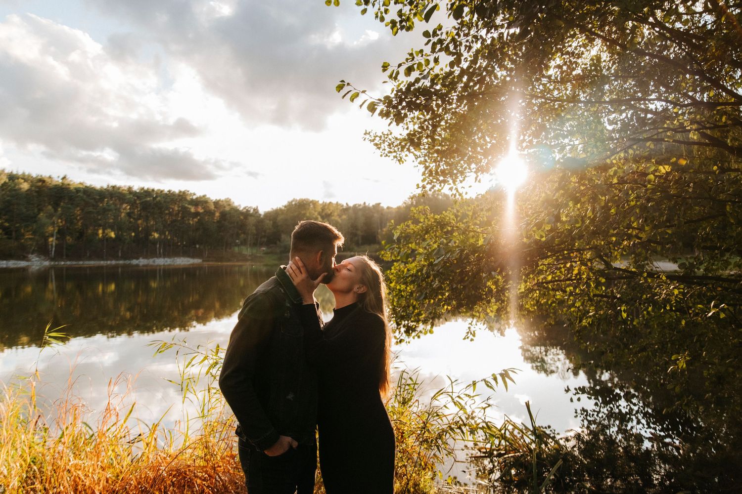 Silhouetted figures share an intimate moment against a dramatic sunset sky.