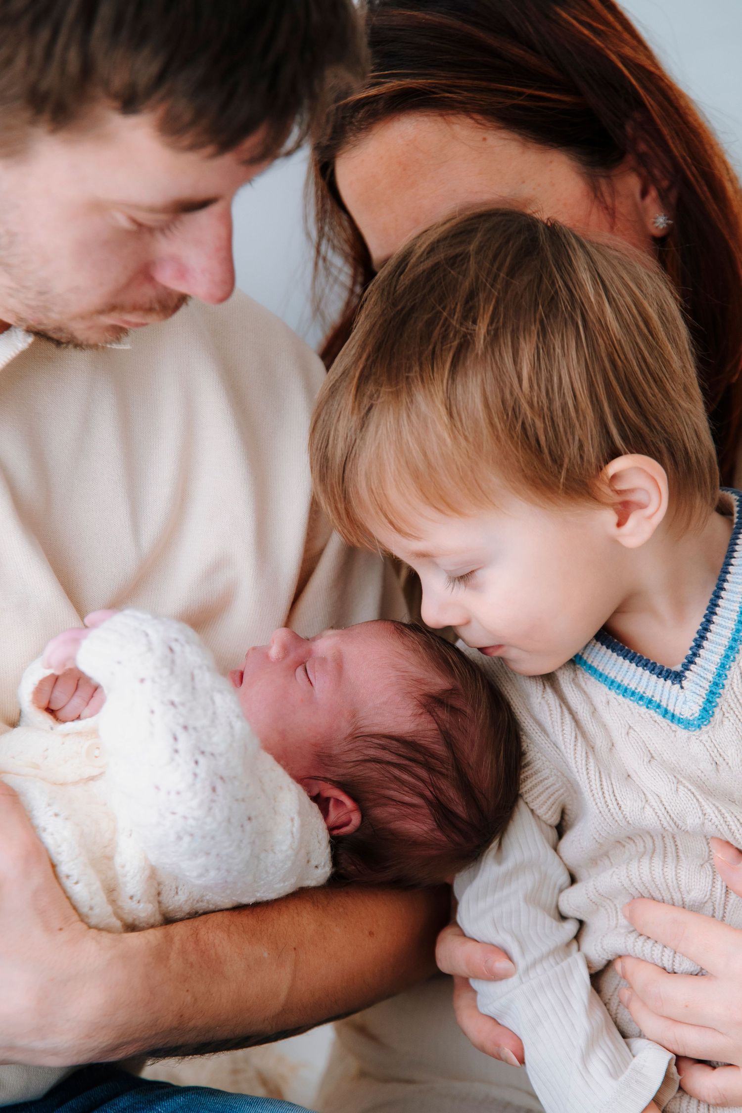 Series of tender moments with newborn baby in white clothing.