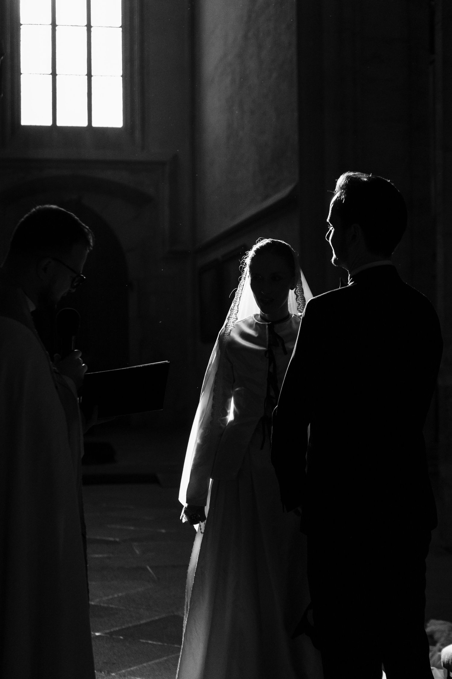 Dramatic black and white silhouettes of figures in a dark interior space with light streaming through windows.