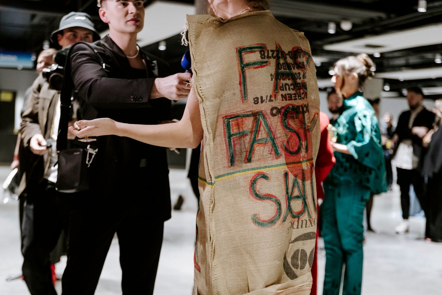 Protesters hold signs and gather in a crowd during a demonstration at an indoor venue.