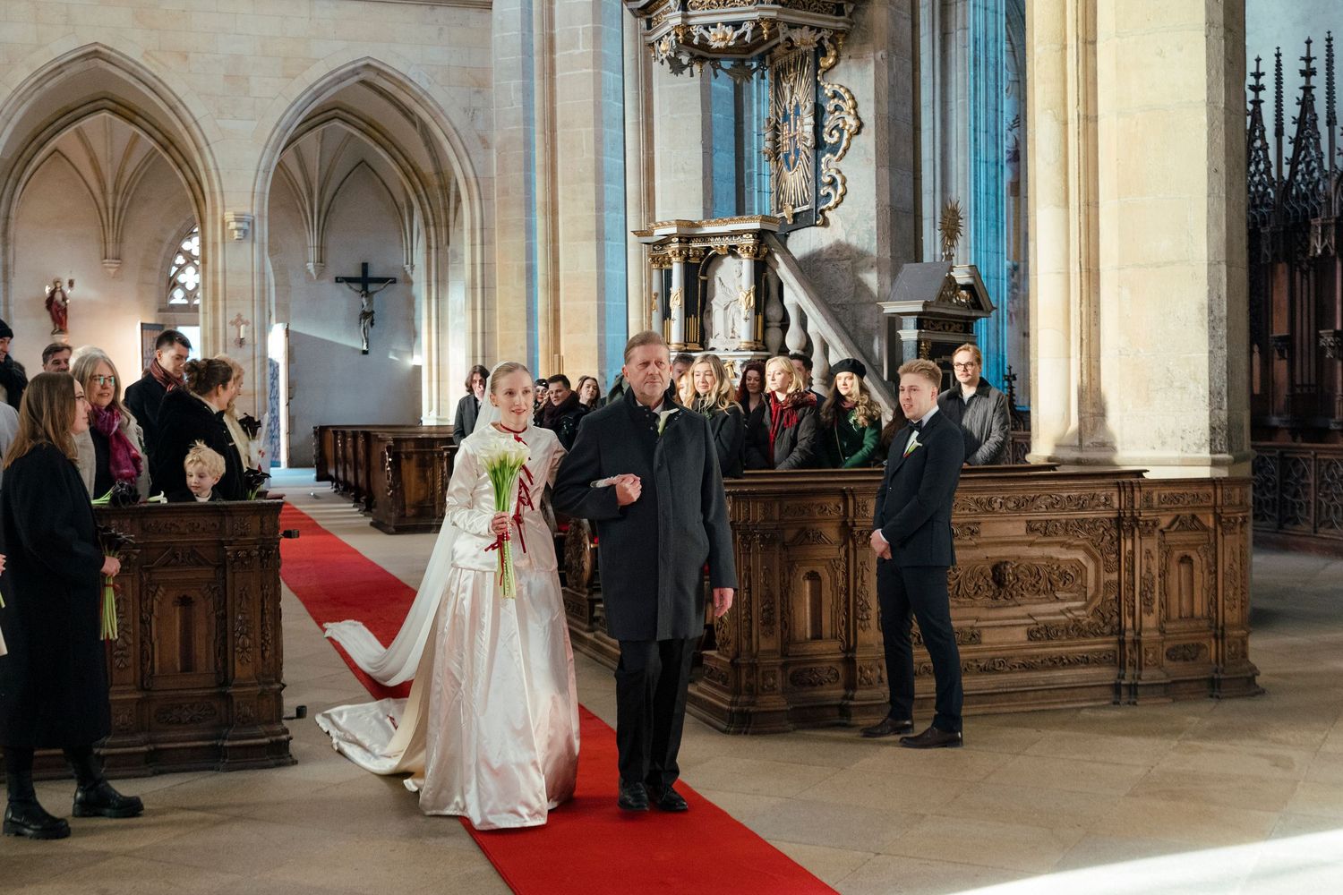 Wedding ceremony taking place inside a grand cathedral with Gothic arches and ornate architectural details.