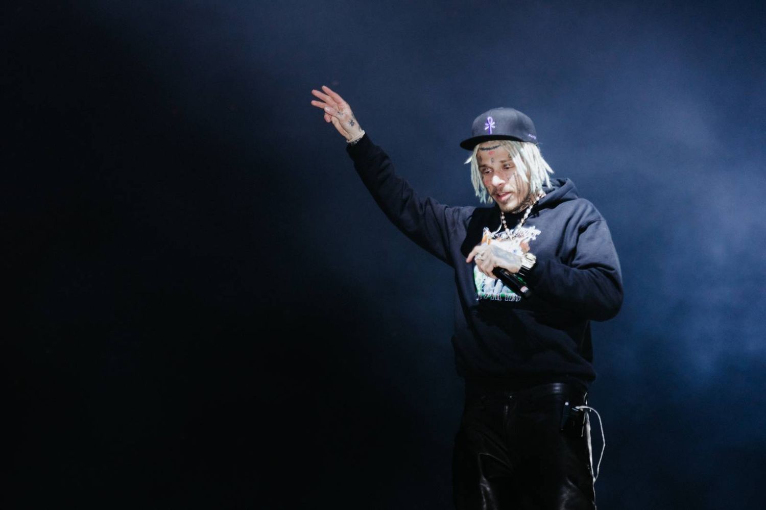 A dramatic performance on stage with blue lighting and fog effects creates an atmospheric theatrical scene.