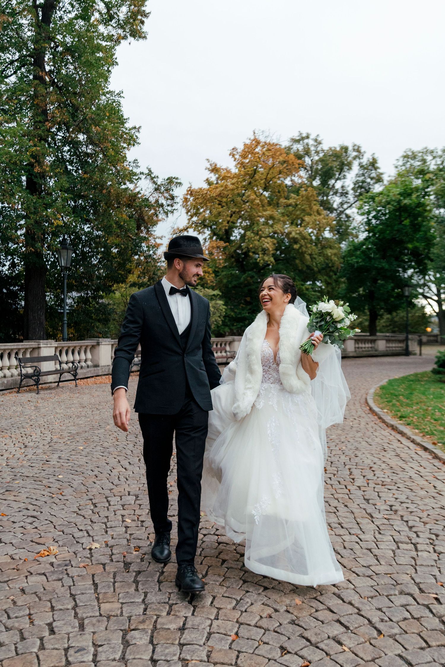 Couple walking and laughing together on cobblestone path.