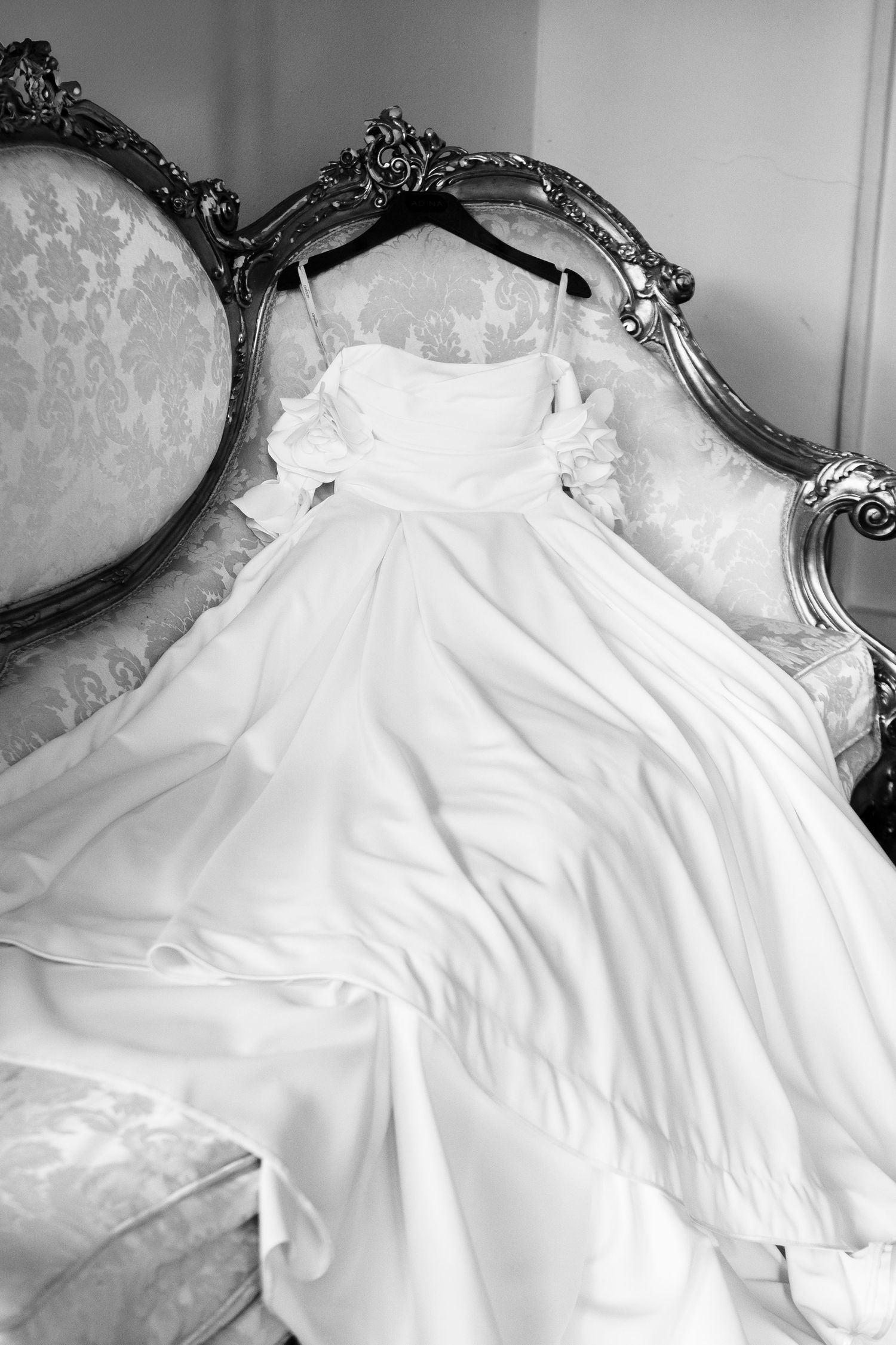 Elegant white wedding dress details laid out on an ornate vintage couch.