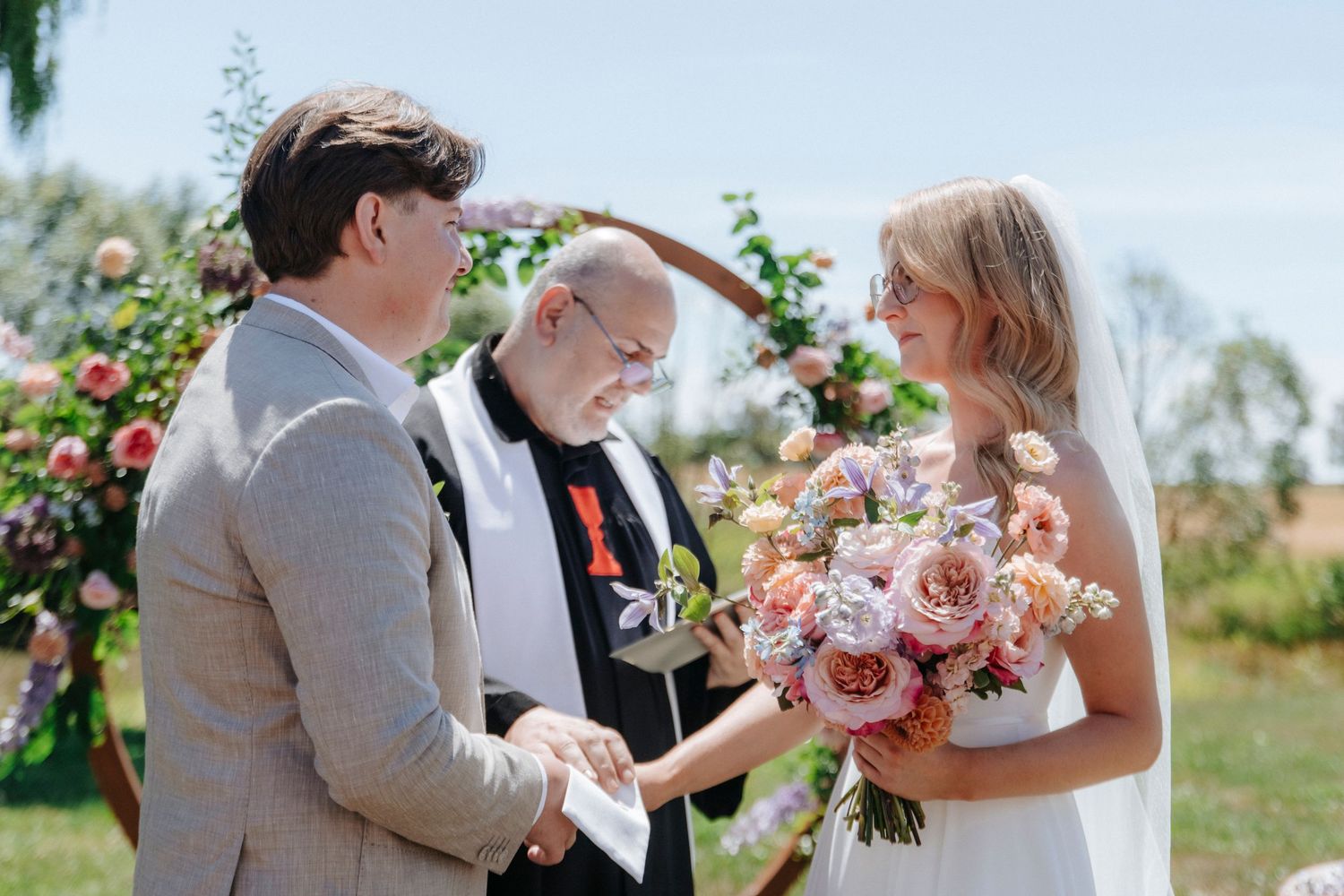 Outdoor garden wedding ceremony with floral arch and natural decor.