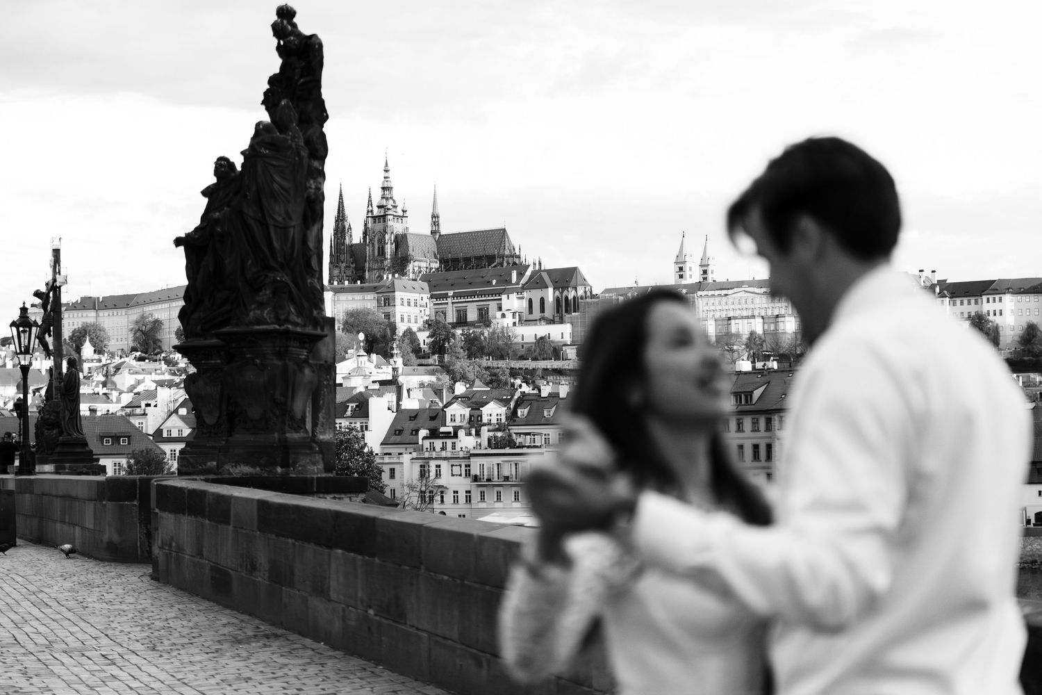 Silhouetted couple sharing intimate moment against city skyline backdrop.