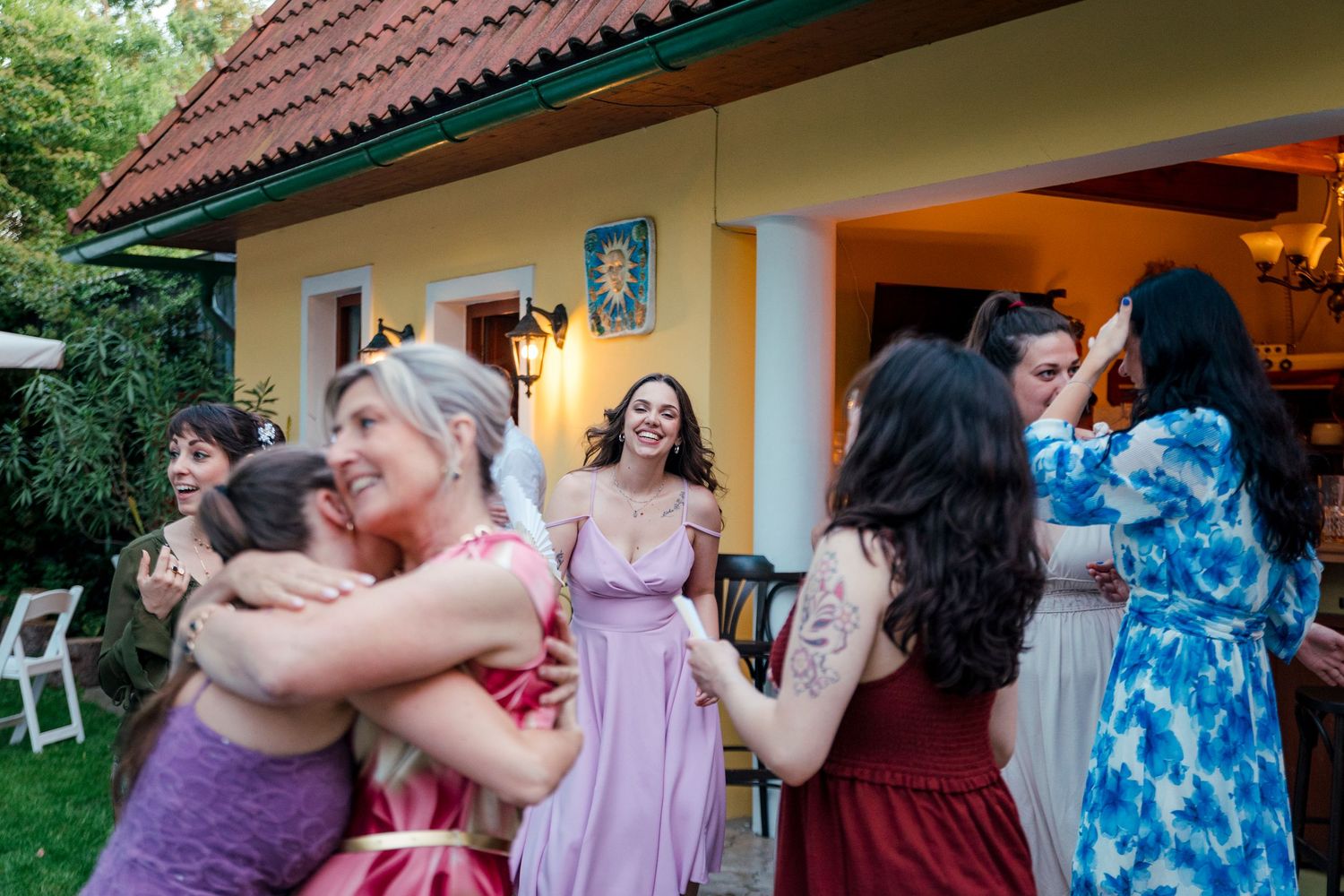 Wedding guests embracing and celebrating at an outdoor venue with colorful dresses.
