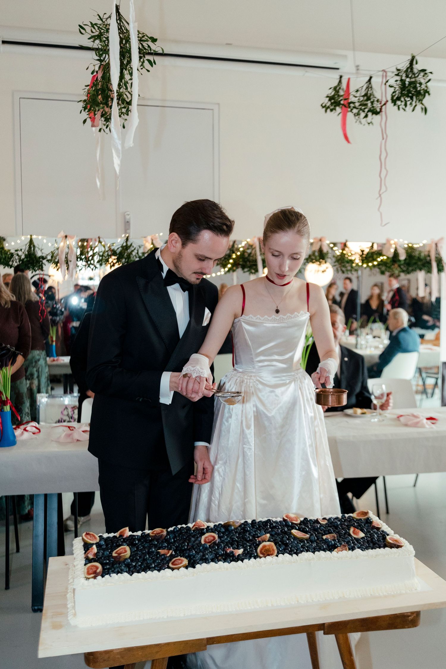 Couple sharing a joyful moment at their wedding reception while viewing a long display table of desserts.