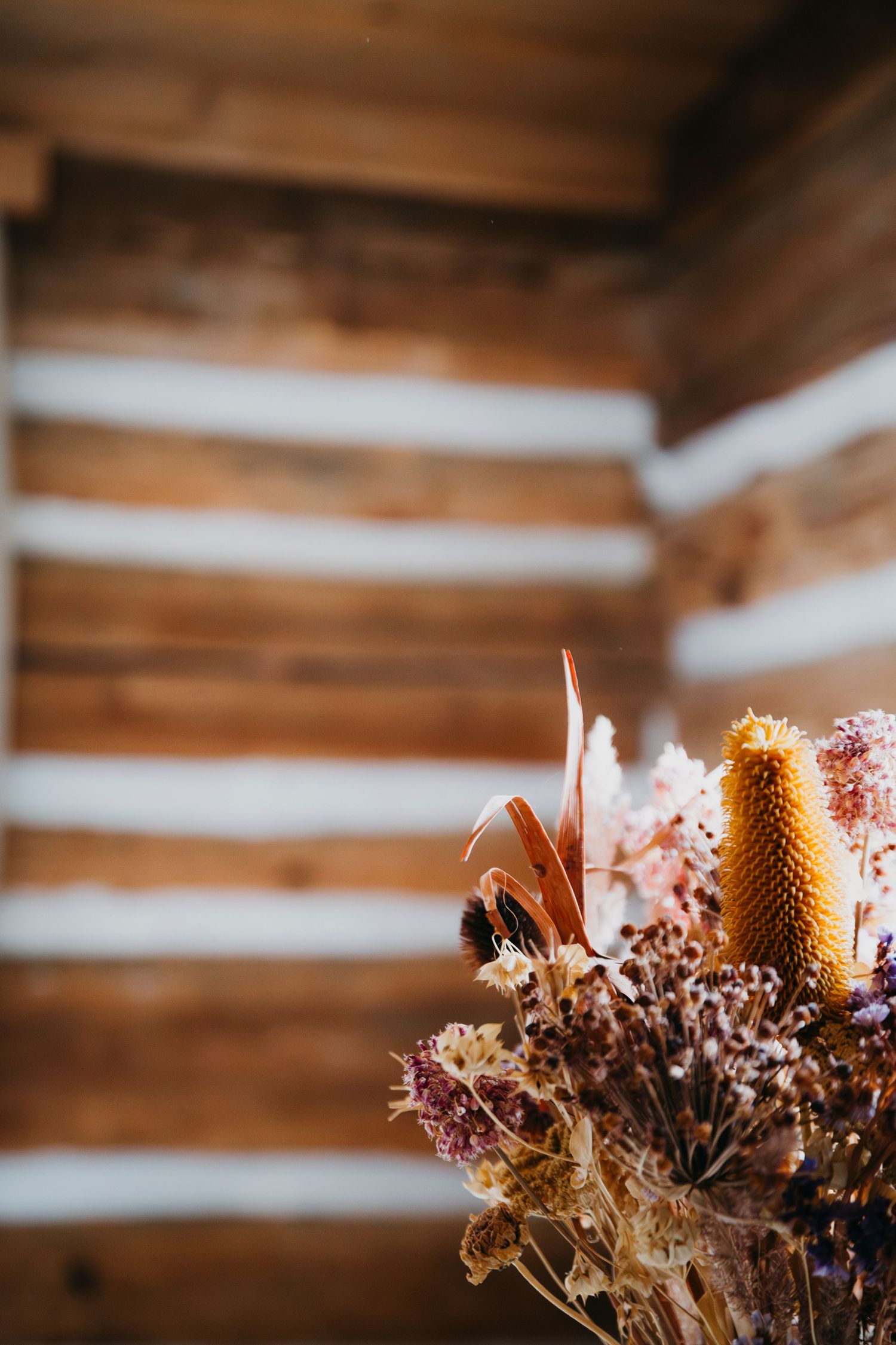 Rustic wooden ceiling with dried flowers and candles creating warm ambient lighting.