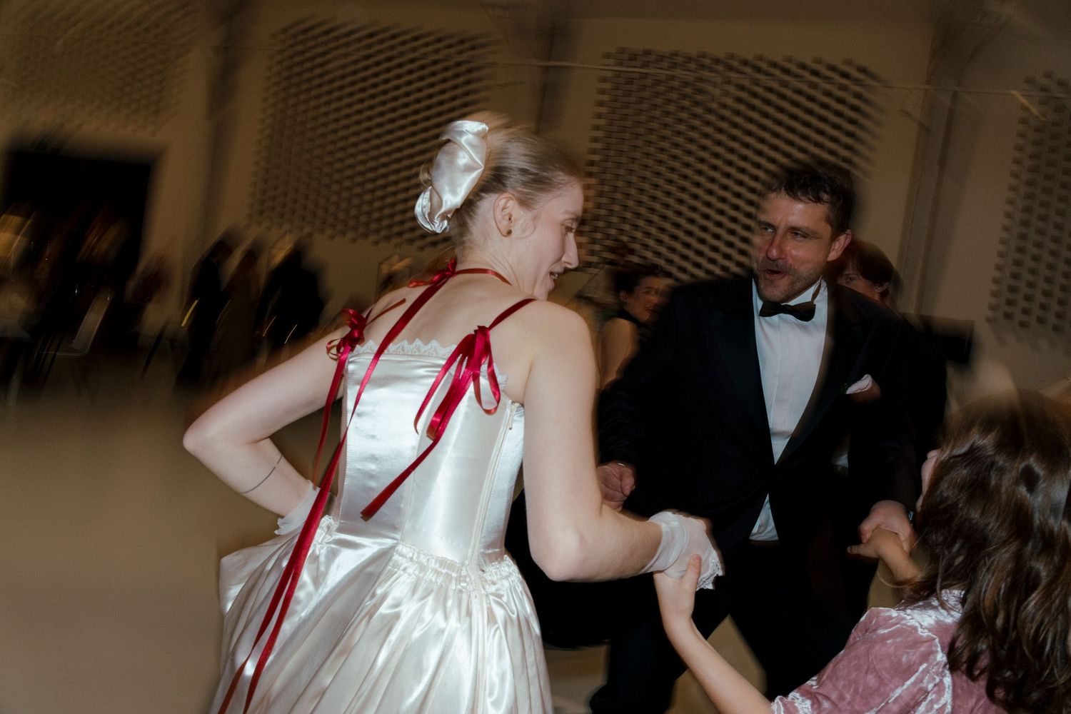 Wedding guests dance together in formal attire during a reception celebration on a dance floor.