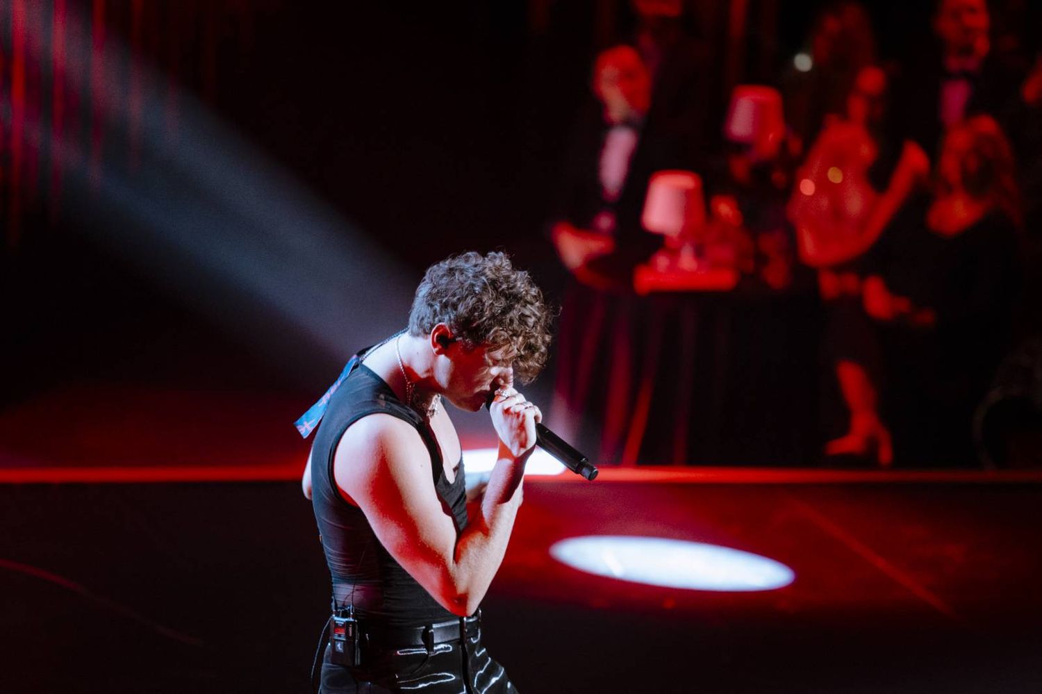 Concert performer on stage bathed in dramatic red lighting during an energetic live music performance.