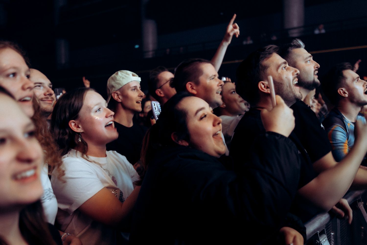 Concert crowd looks up at stage with excitement and anticipation during live performance.