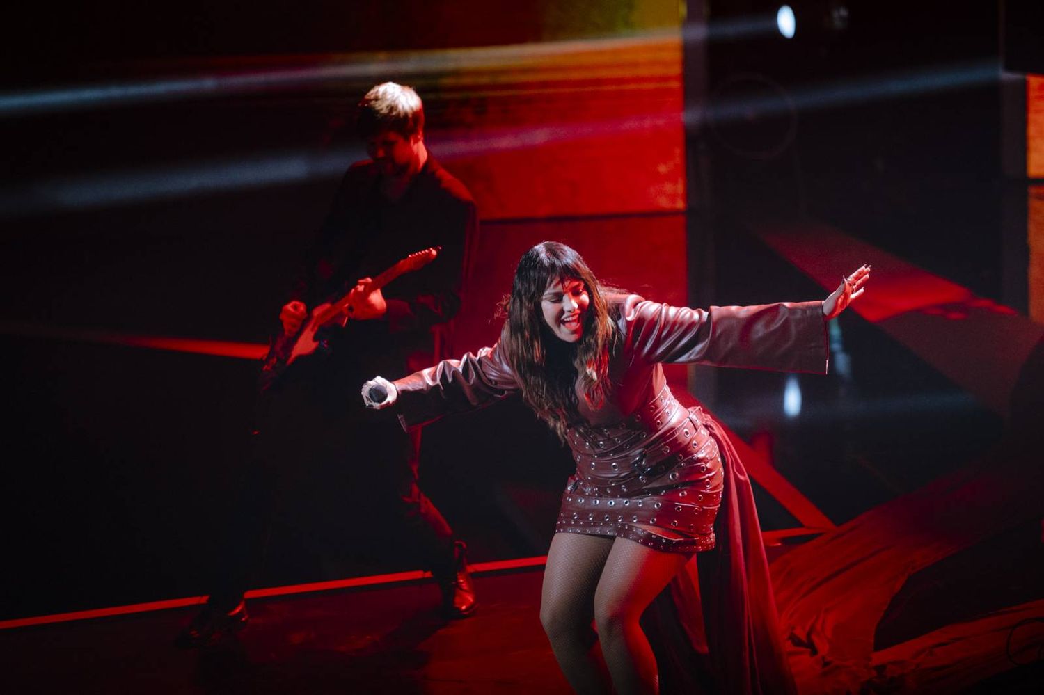 Dynamic stage performance with red lighting effects and theatrical smoke.