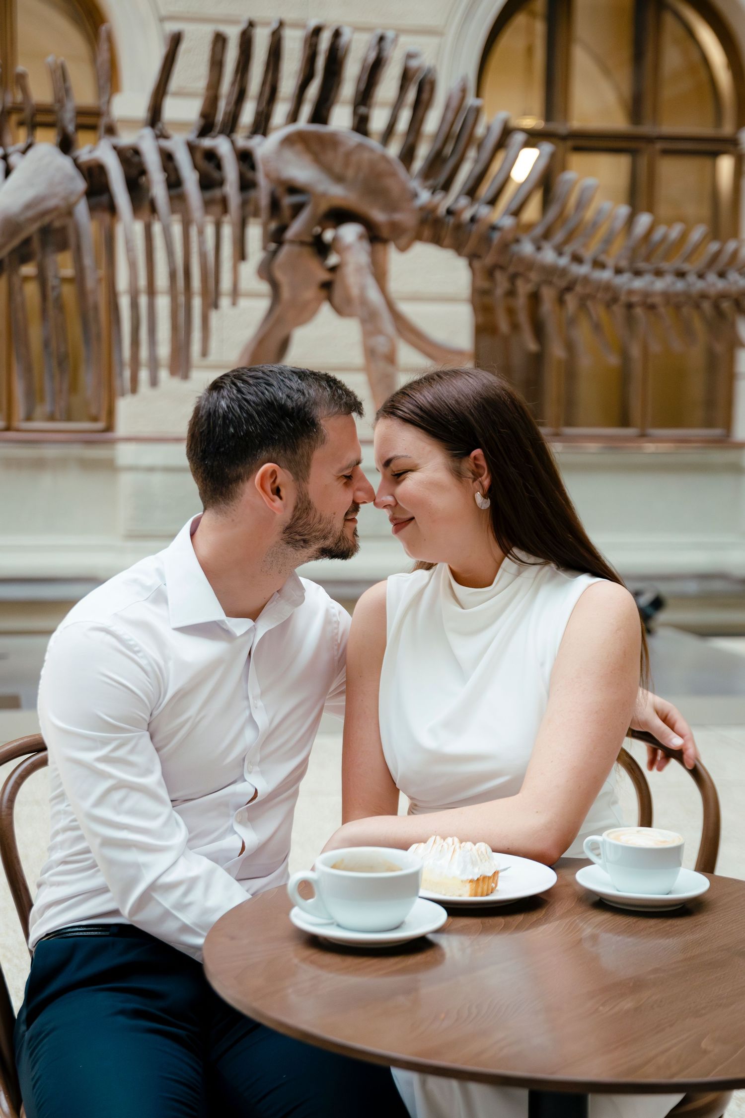 Couple sharing intimate moments over coffee and dessert in a museum cafe setting.
