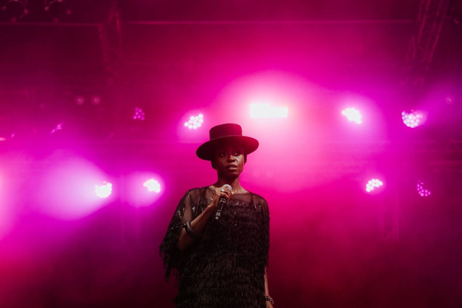 Silhouetted performer on stage illuminated by vibrant pink and purple concert lighting during a live show.