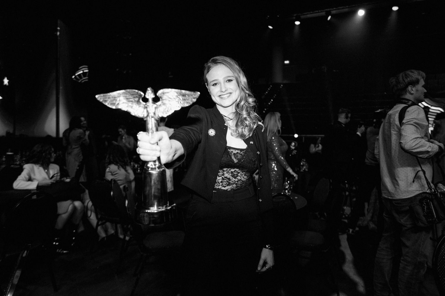 A person in black holds a white bird in a dark indoor setting with spotlights.