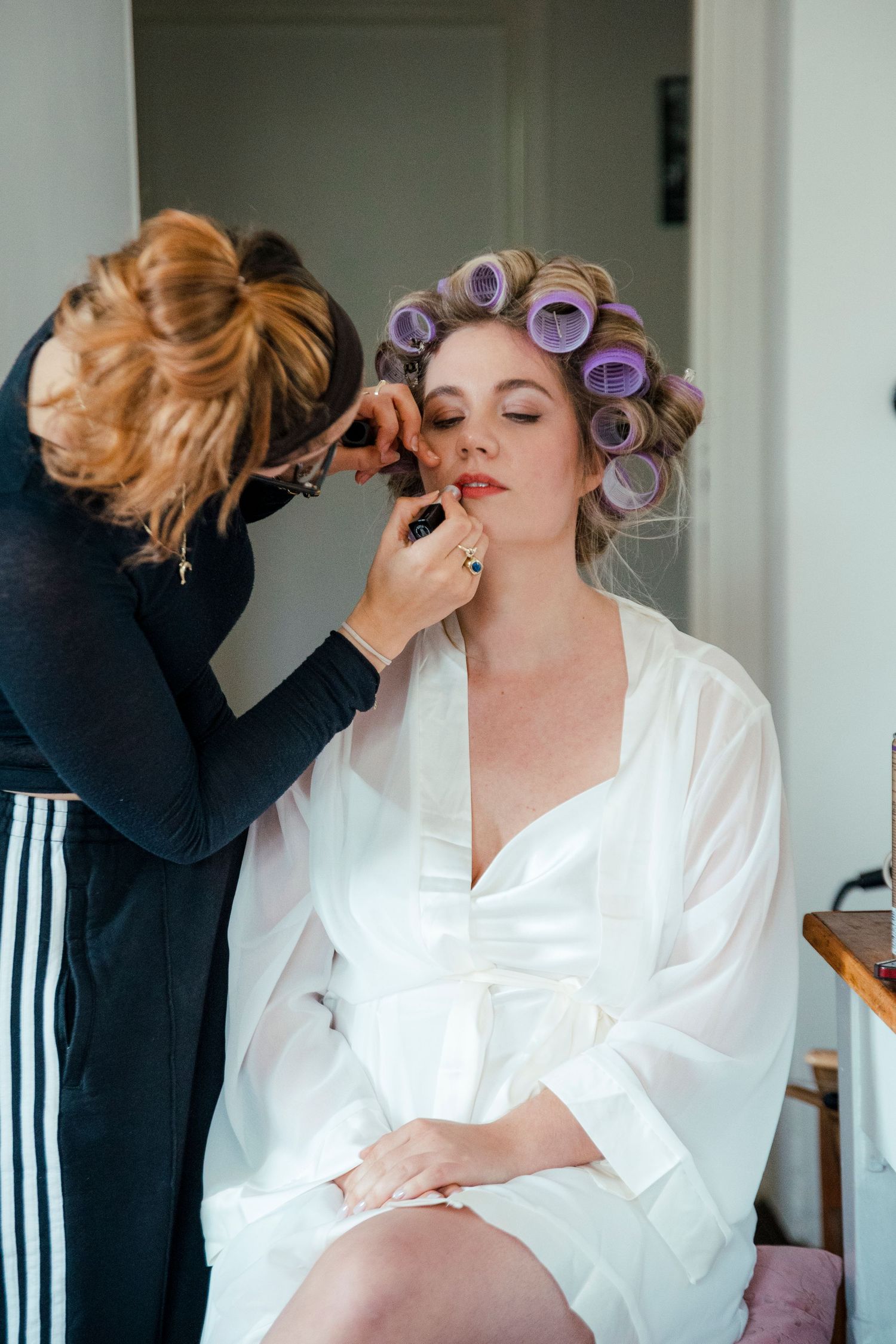 Getting ready scene with hair styling and makeup preparation in white robes.