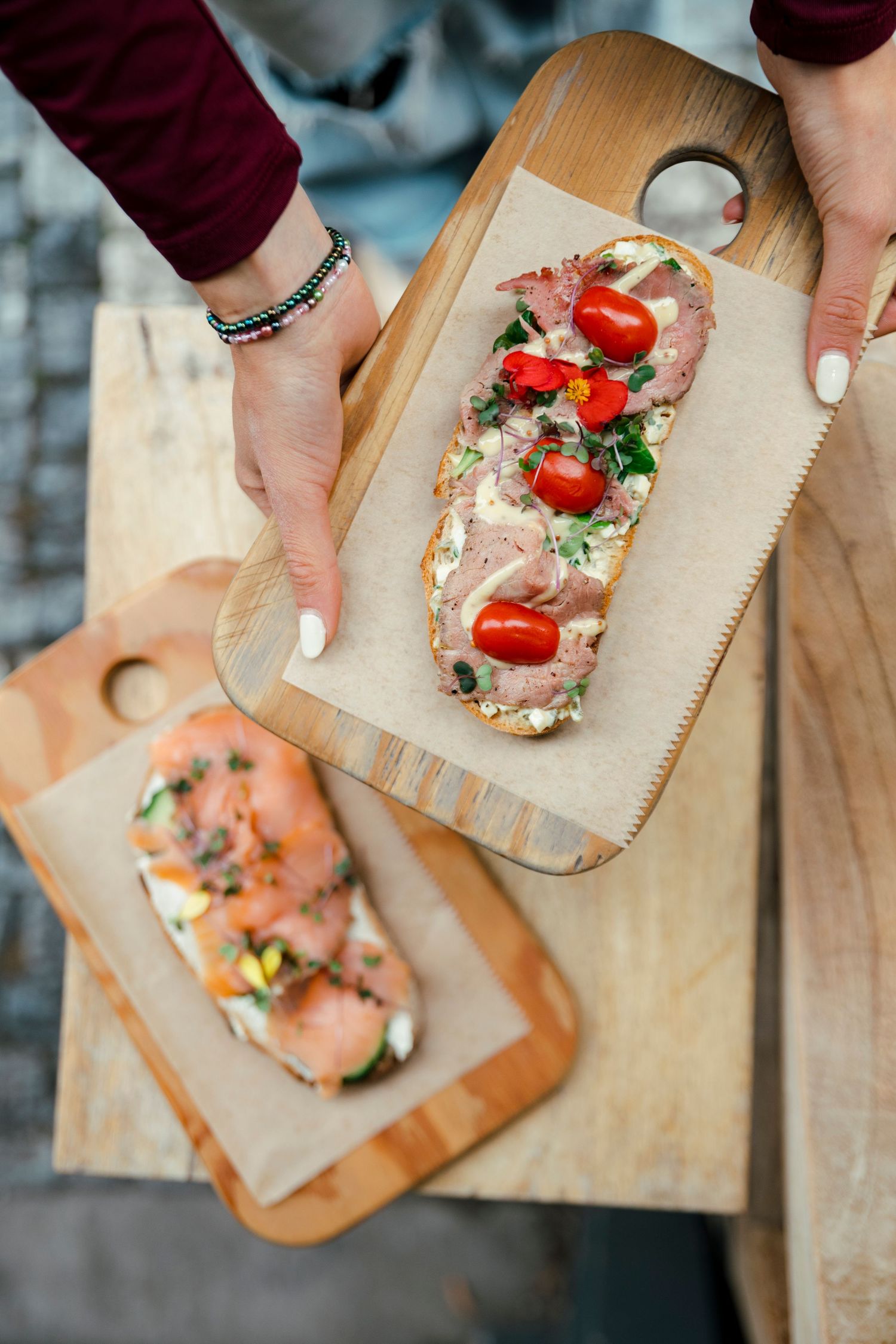 Hands arranging fresh ingredients on wooden serving boards with garnishes.