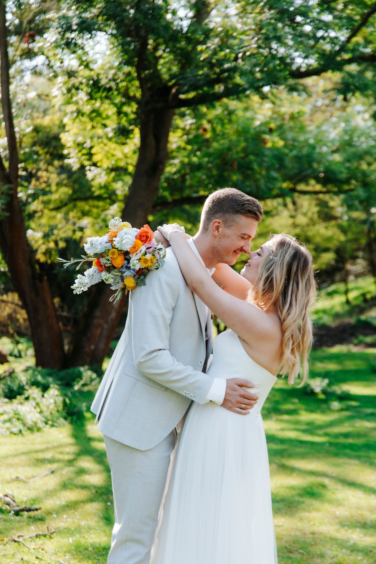 Romantic outdoor wedding portraits in a sunlit garden setting.