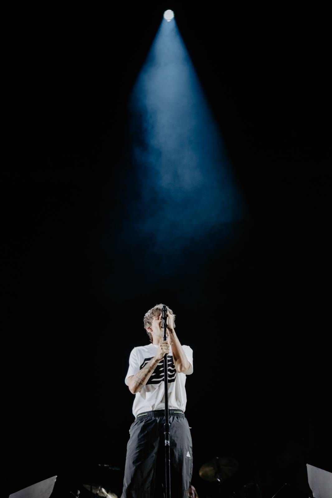 Solo performer on dark stage illuminated by single blue spotlight from above.