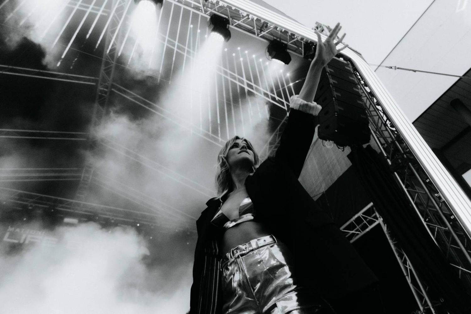 Black and white concert photo showing silhouettes of performers on stage with dramatic lighting and fog.