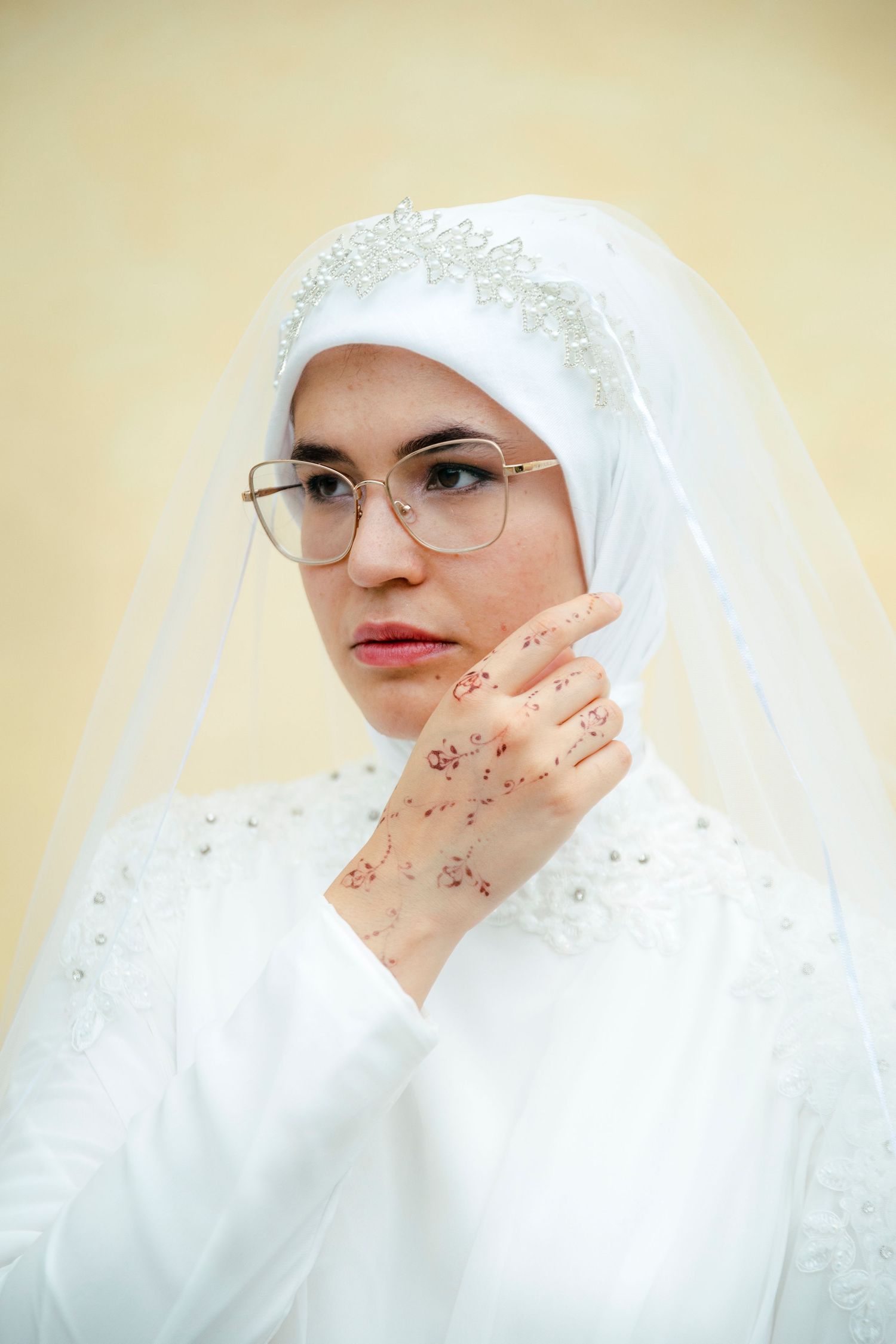 Close-up sequence of a bride in white hijab with delicate embellishments and glasses.