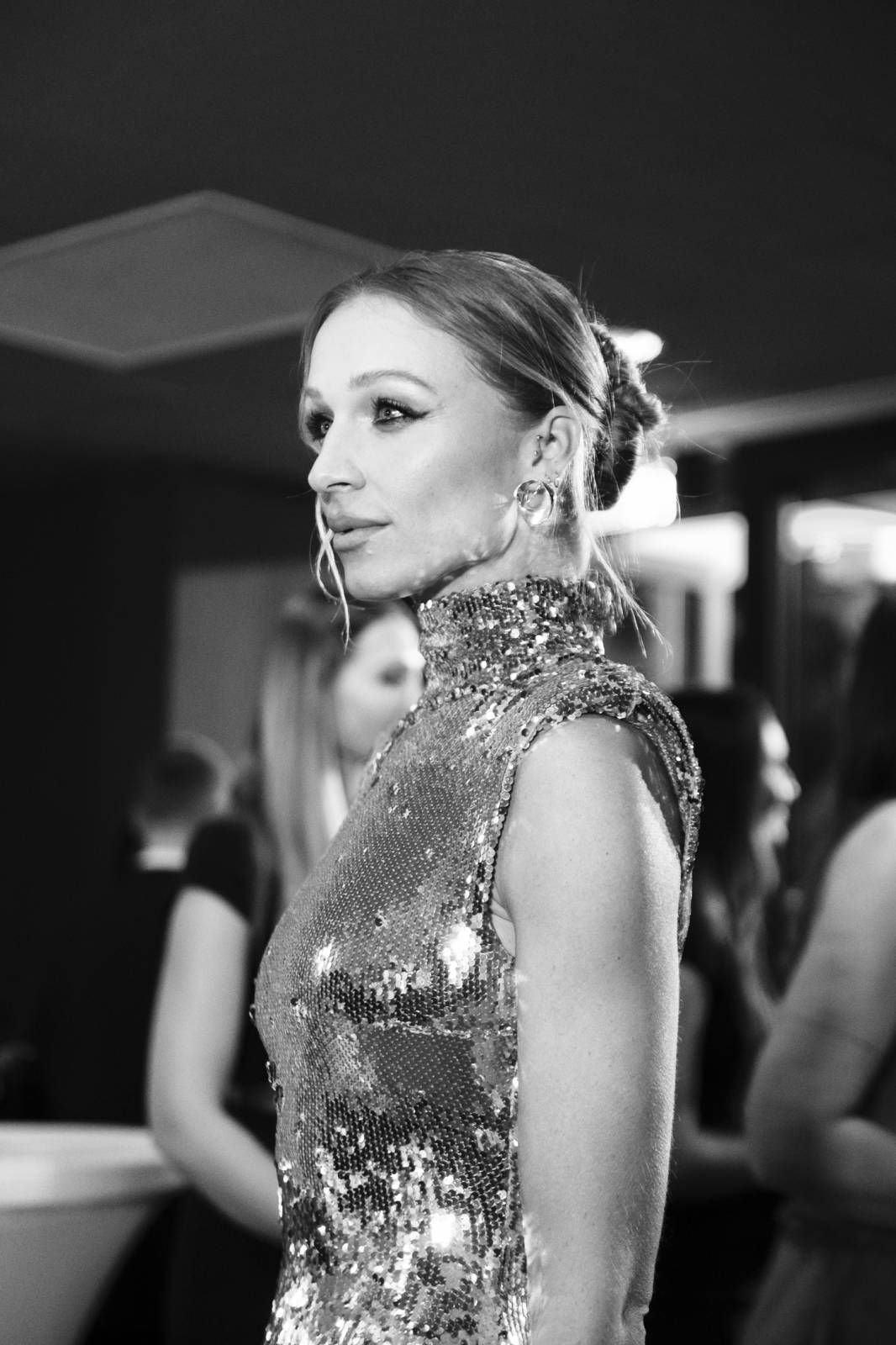 Performer wearing a sparkling silver sequined outfit in a dark venue setting.