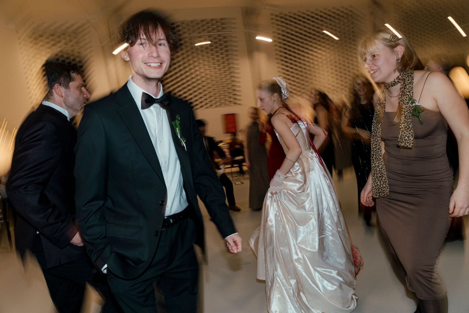 Wedding reception guests dancing and celebrating in a modern venue with reflective ceiling panels.