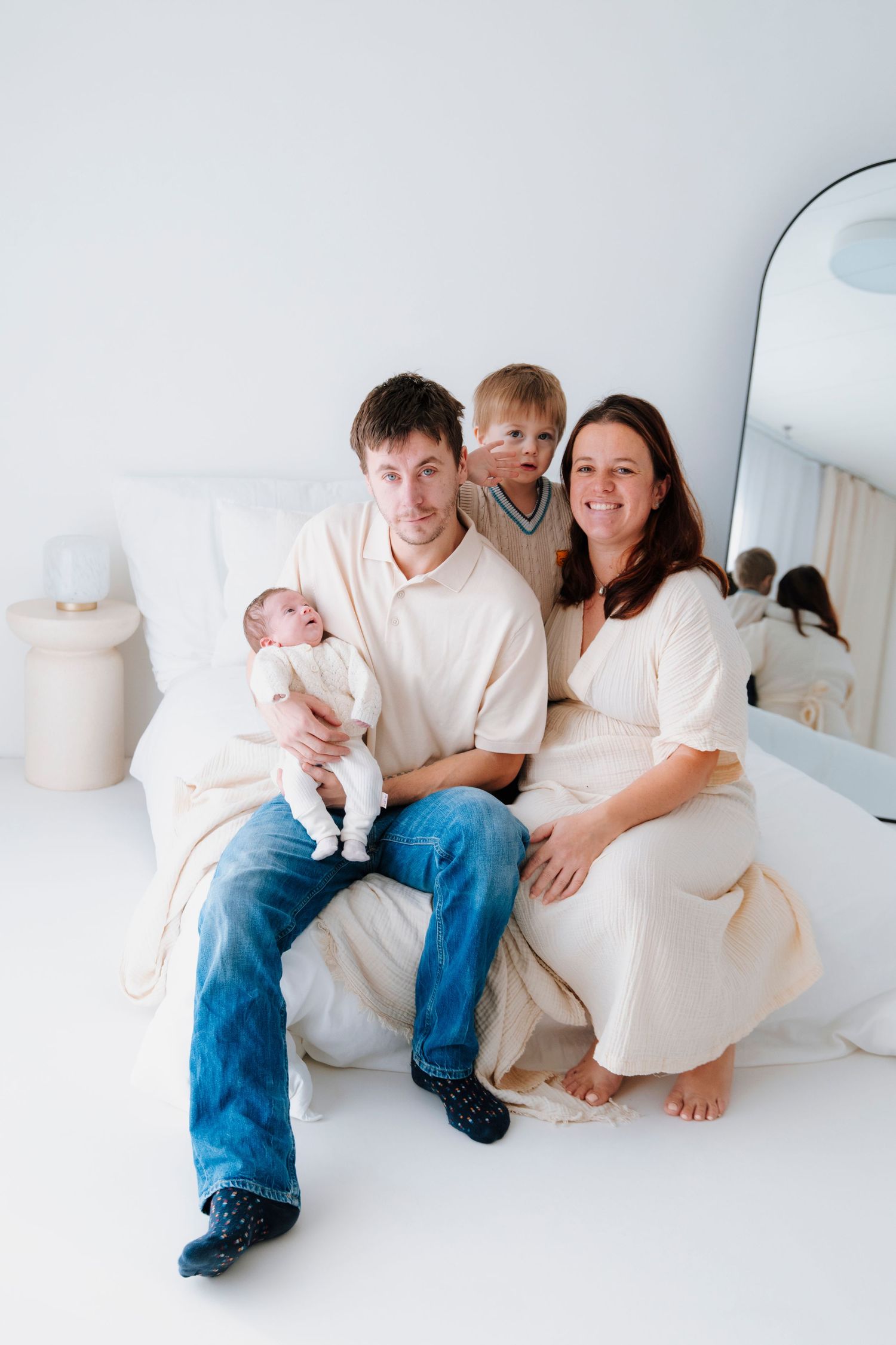 Family lounging together on white furniture in bright minimalist room.