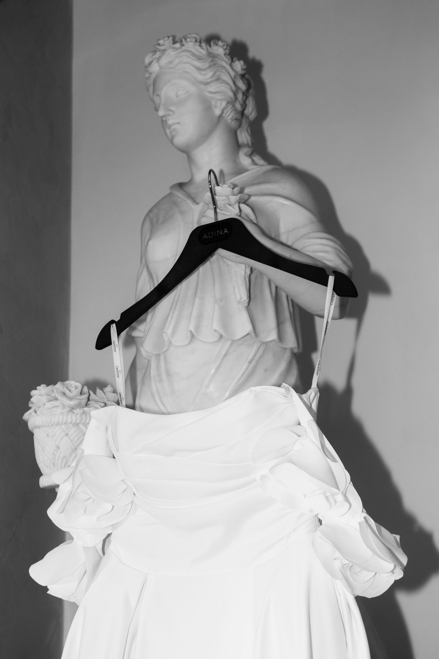 Elegant white wedding dress details shown on dress form against neutral background.