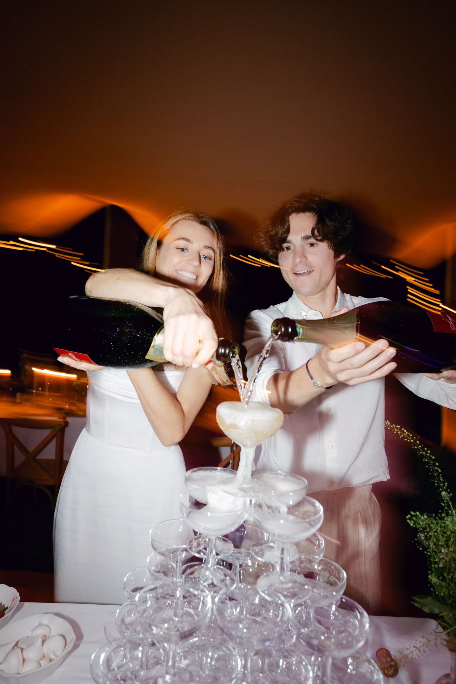 Les jeunes mariés versent du champagne dans une élégante tour de verres lors de la célébration du mariage.