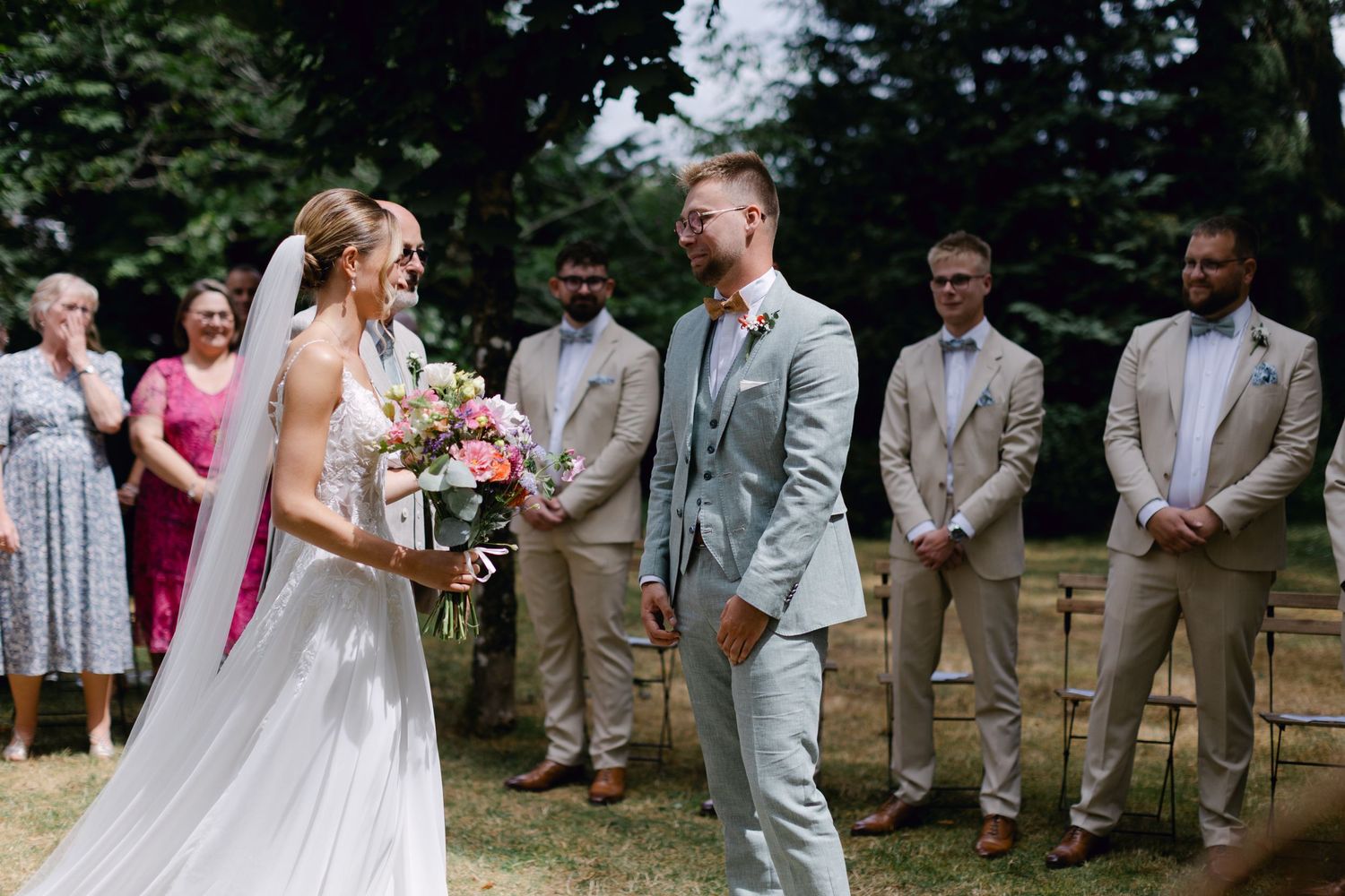 La mariée et le marié partagent un joyeux premier regard lors de la cérémonie de mariage en plein air.