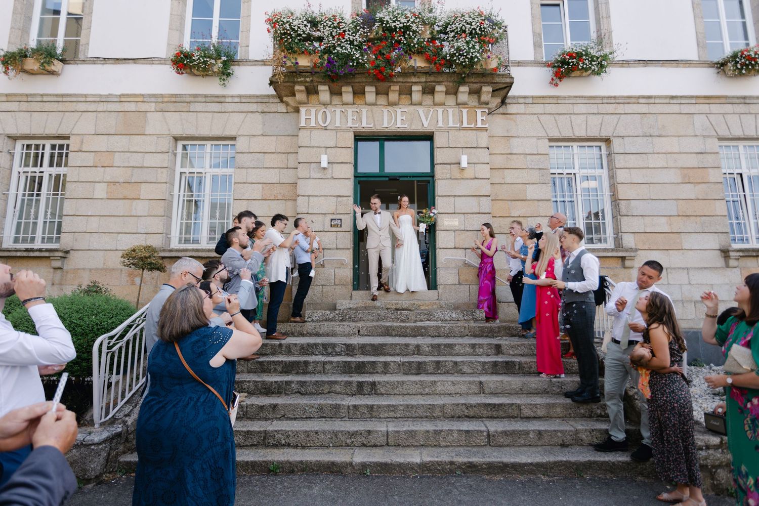 Les jeunes mariés sont célébrés par des invités jetant des confettis sur les marches de l'hôtel de ville après une cérémonie civile.