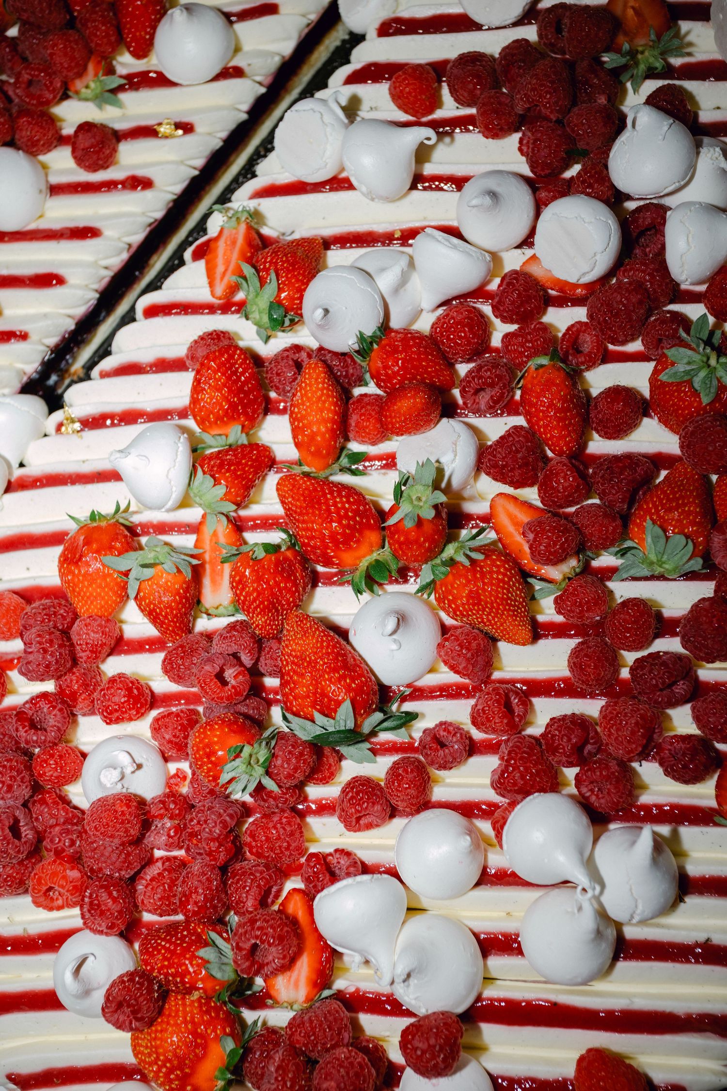 Gros plan d'un gâteau de mariage garni de fraises fraîches, de framboises et de crème blanche.