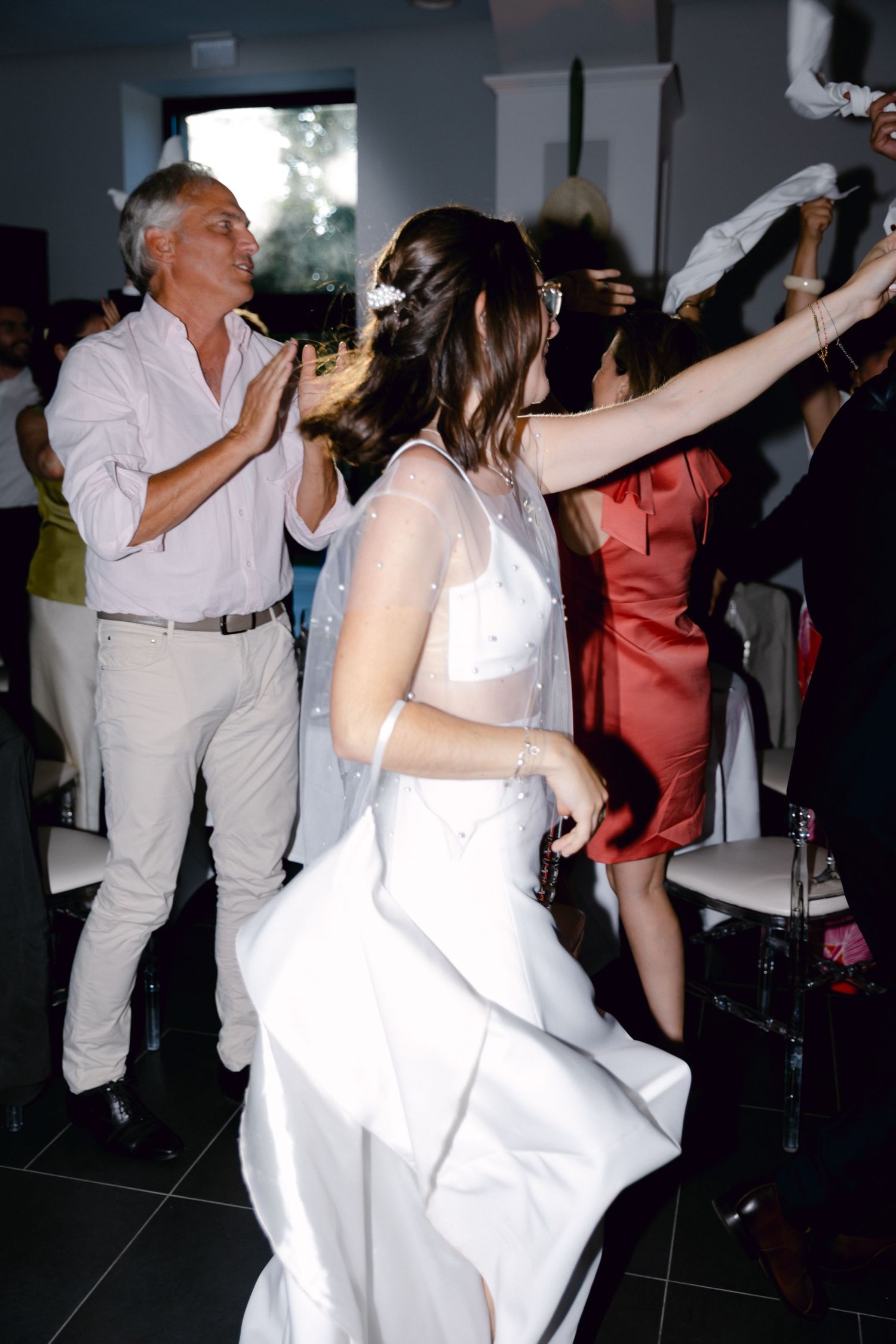 Mariée en robe blanche dansant joyeusement avec des invités lors d'une réception de mariage.