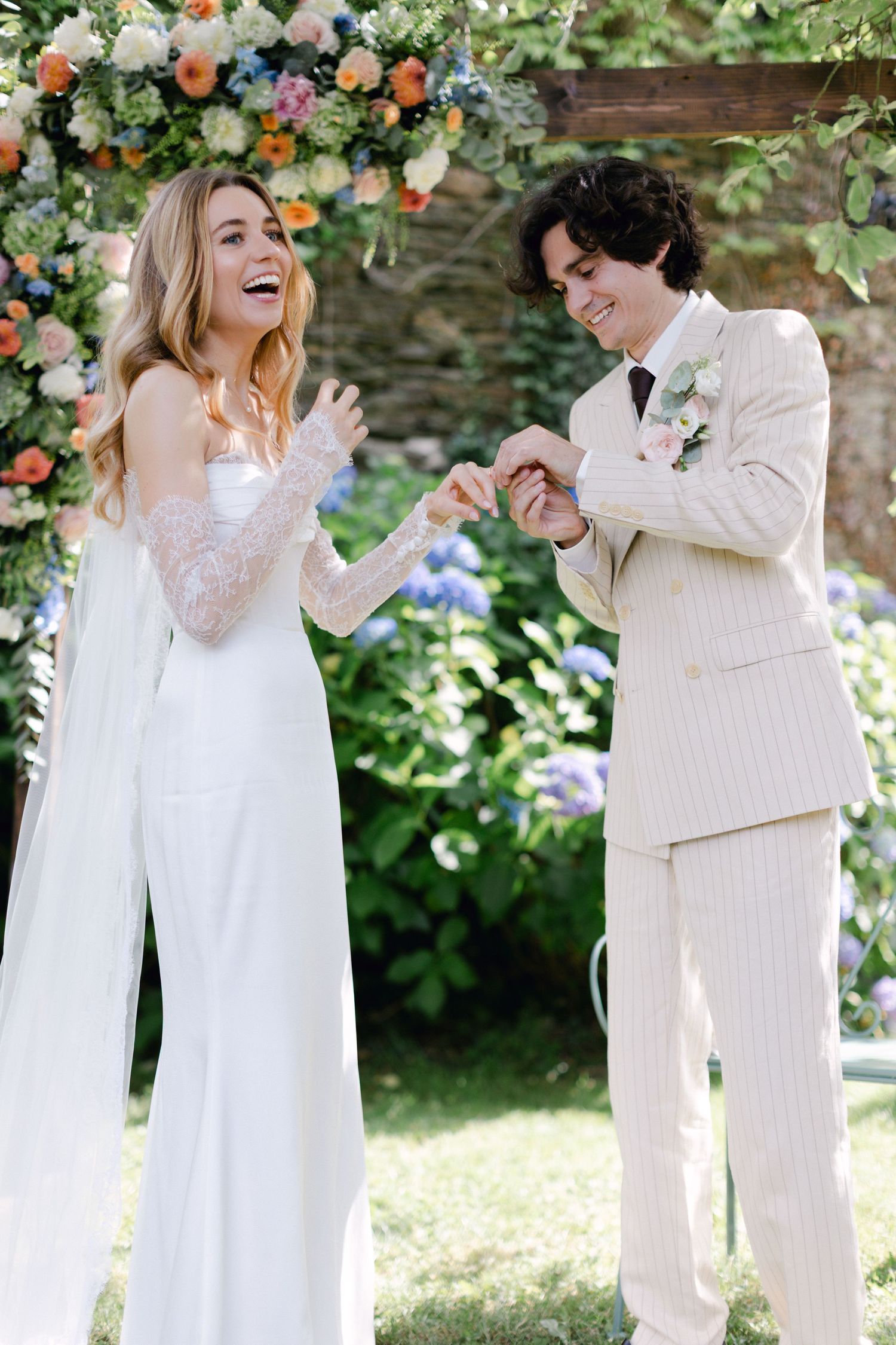 Mariée rieuse et marié souriant se tenant la main lors d'une joyeuse cérémonie de mariage en plein air.
