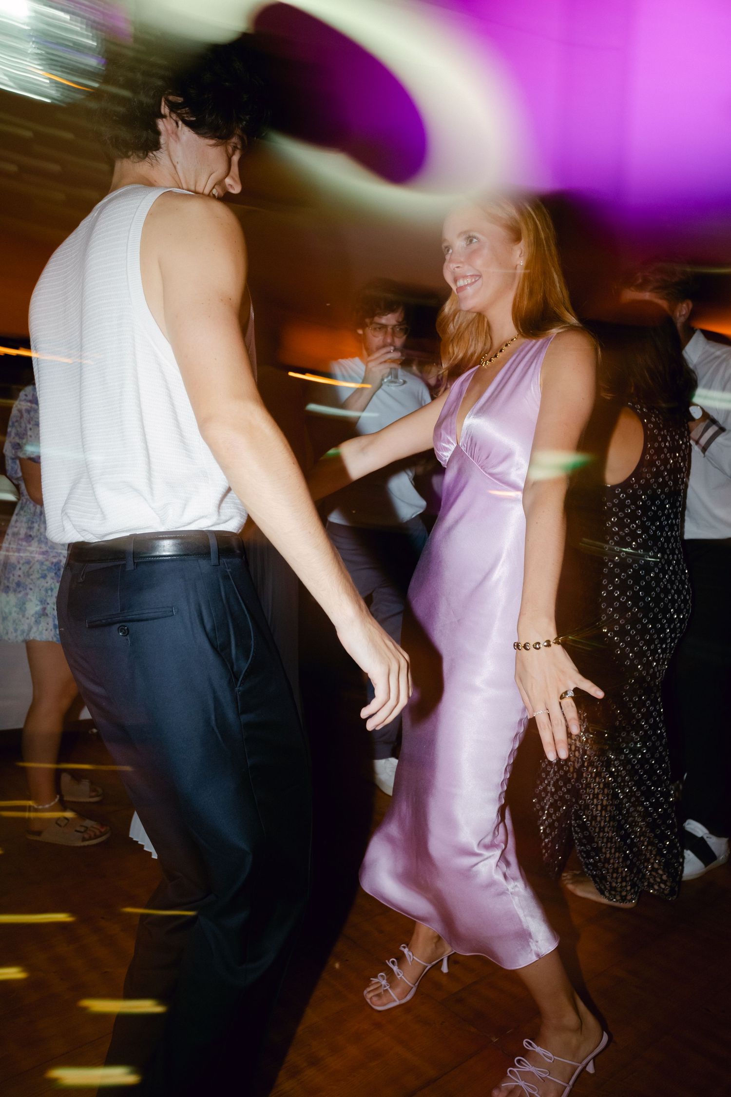 Couple dansant ensemble sur la piste de danse de réception de mariage sous un éclairage violet vibrant.