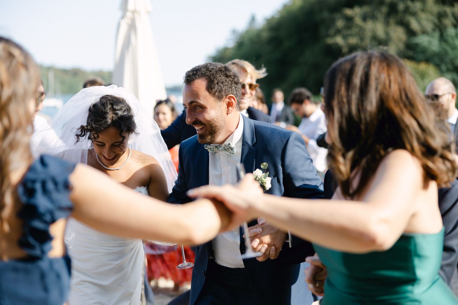 Bride and groom dancing joyfully with guests at an outdoor wedding celebration.