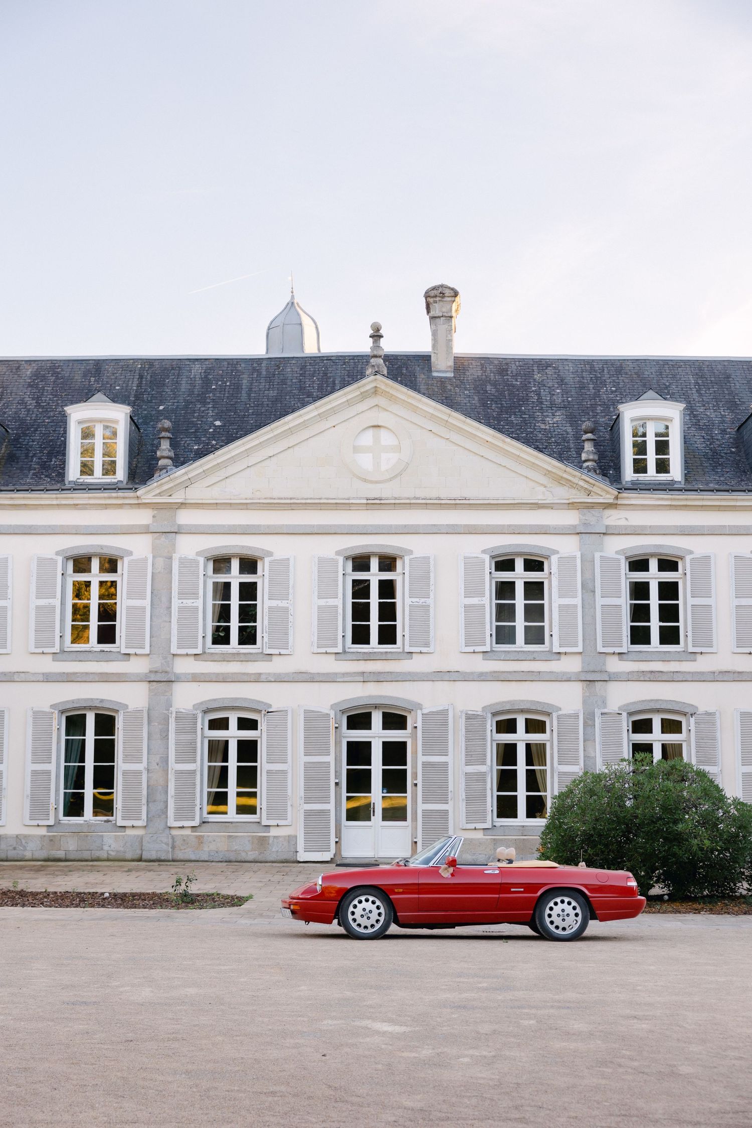 Décapotable rouge voiture de sport garée devant un élégant château français à l'architecture en pierre classique.