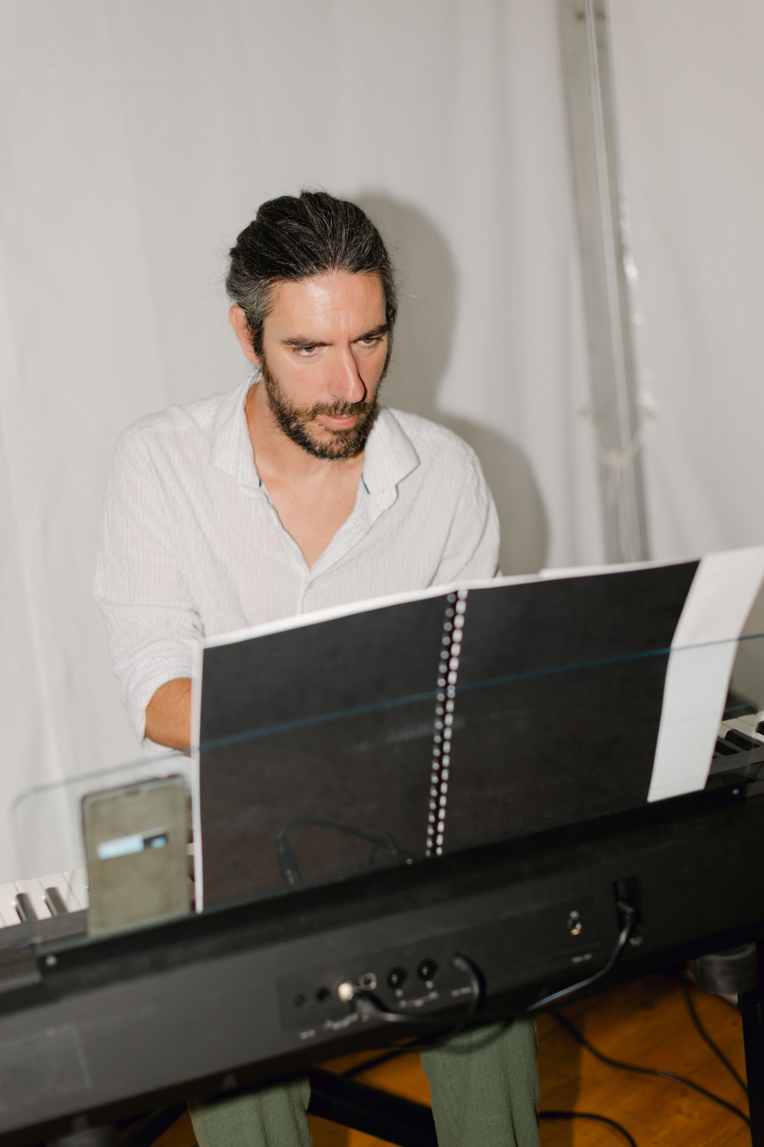 Musicien avec barbe jouant du clavier lors d'une réception de mariage en train de lire des partitions.