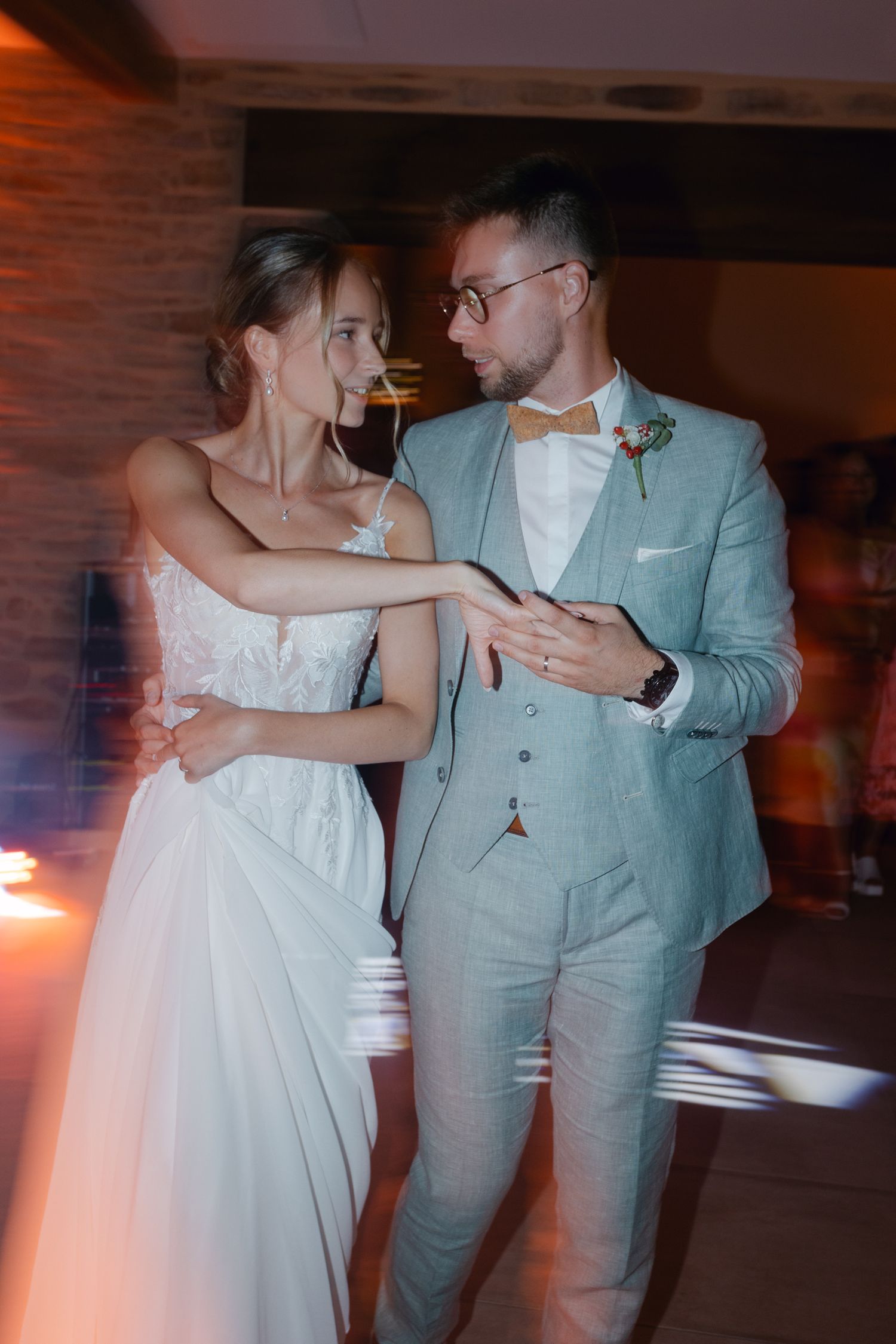 La mariée en robe blanche et le marié en costume trois pièces bleu clair partageant la première danse au mariage.