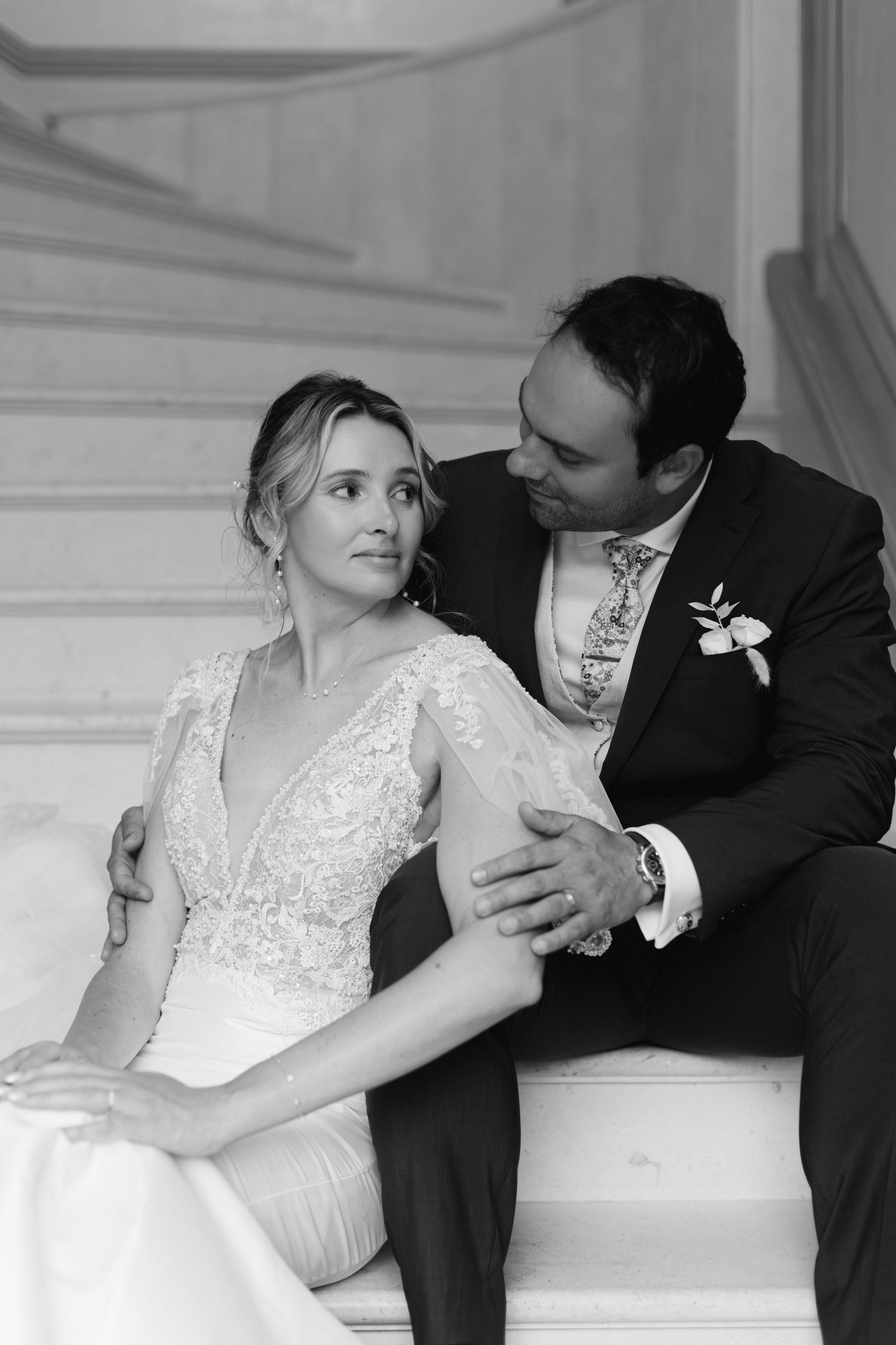 Portrait romantique en noir et blanc de la mariée et du marié partageant un moment intime sur l'escalier de mariage.