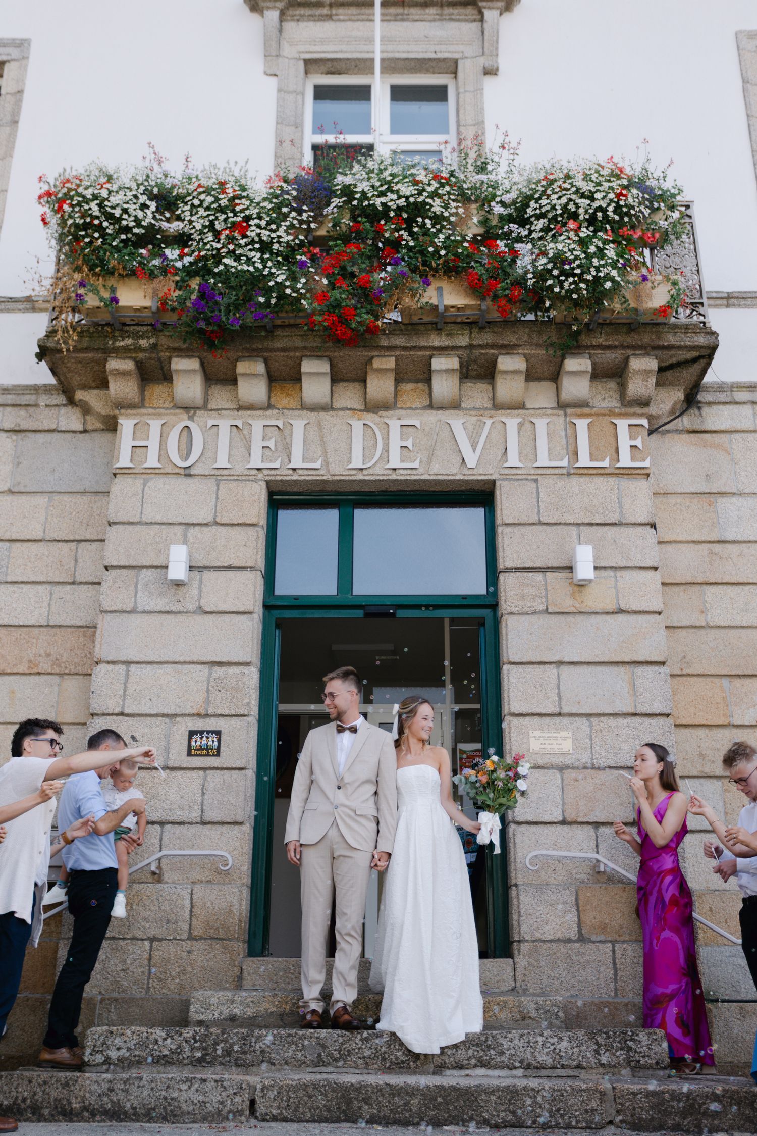 Les jeunes mariés sortent de l'hôtel de ville en France entourés d'invités qui applaudissent après la cérémonie de mariage civil.